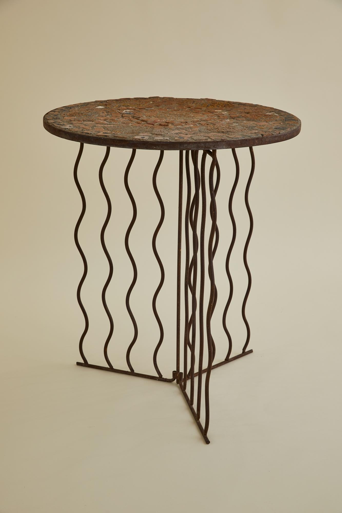 This side table has a rich patina with custom mosaic tile top and a thin tripod base. The base features a modernist iron wave detail. The top is made of square terracotta tile inlays and details of fish. The metal has been sanded and repainted. The