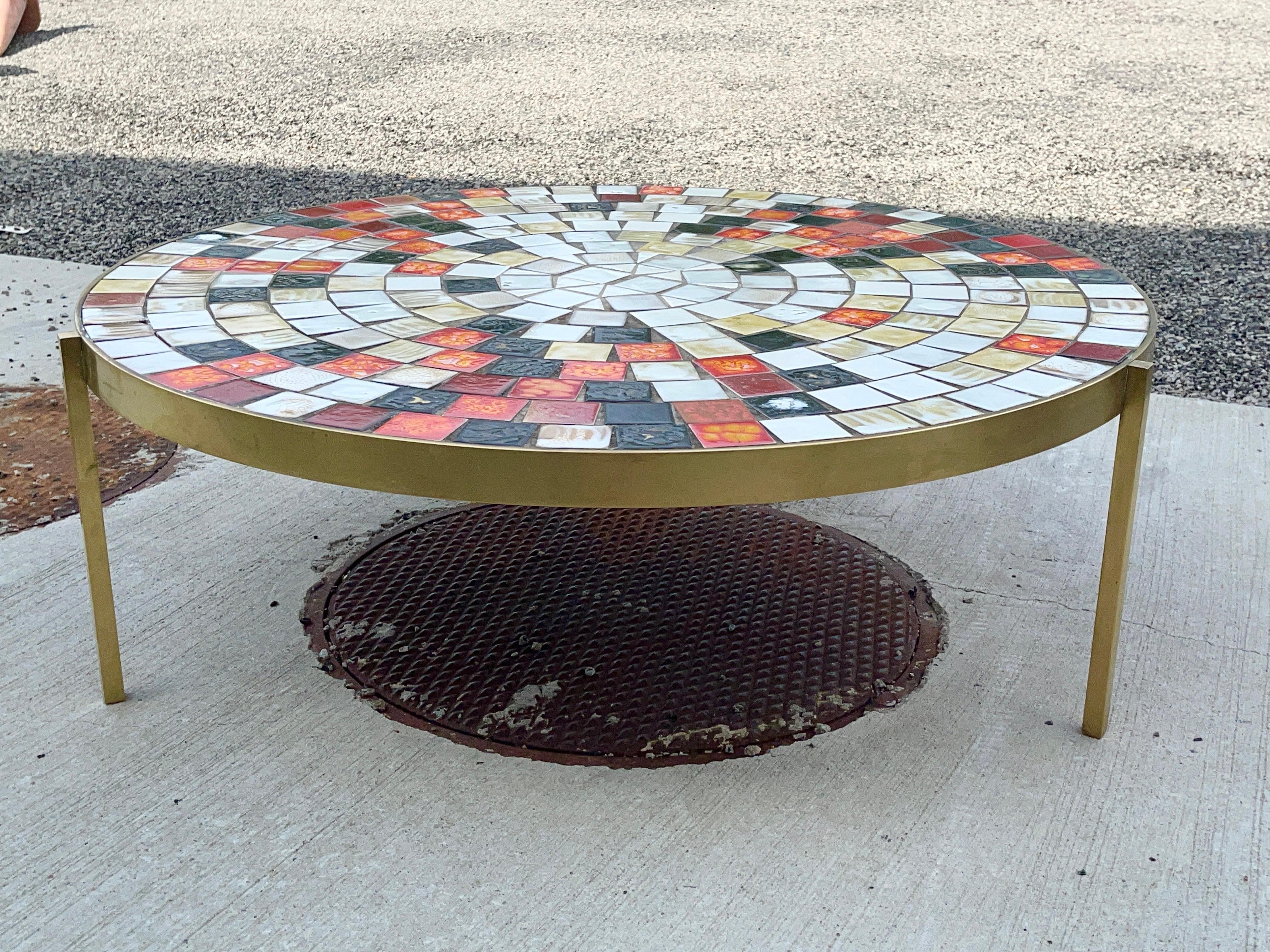 1950’s American mosaic tile and brass coffee table by Mosaic House. 14.5 inches high x 43.5 inches diameter.
Heavy gauge solid brass band on three solid brass square rod legs supporting a plywood substrate tiled with multicolor glazed ceramic tiles