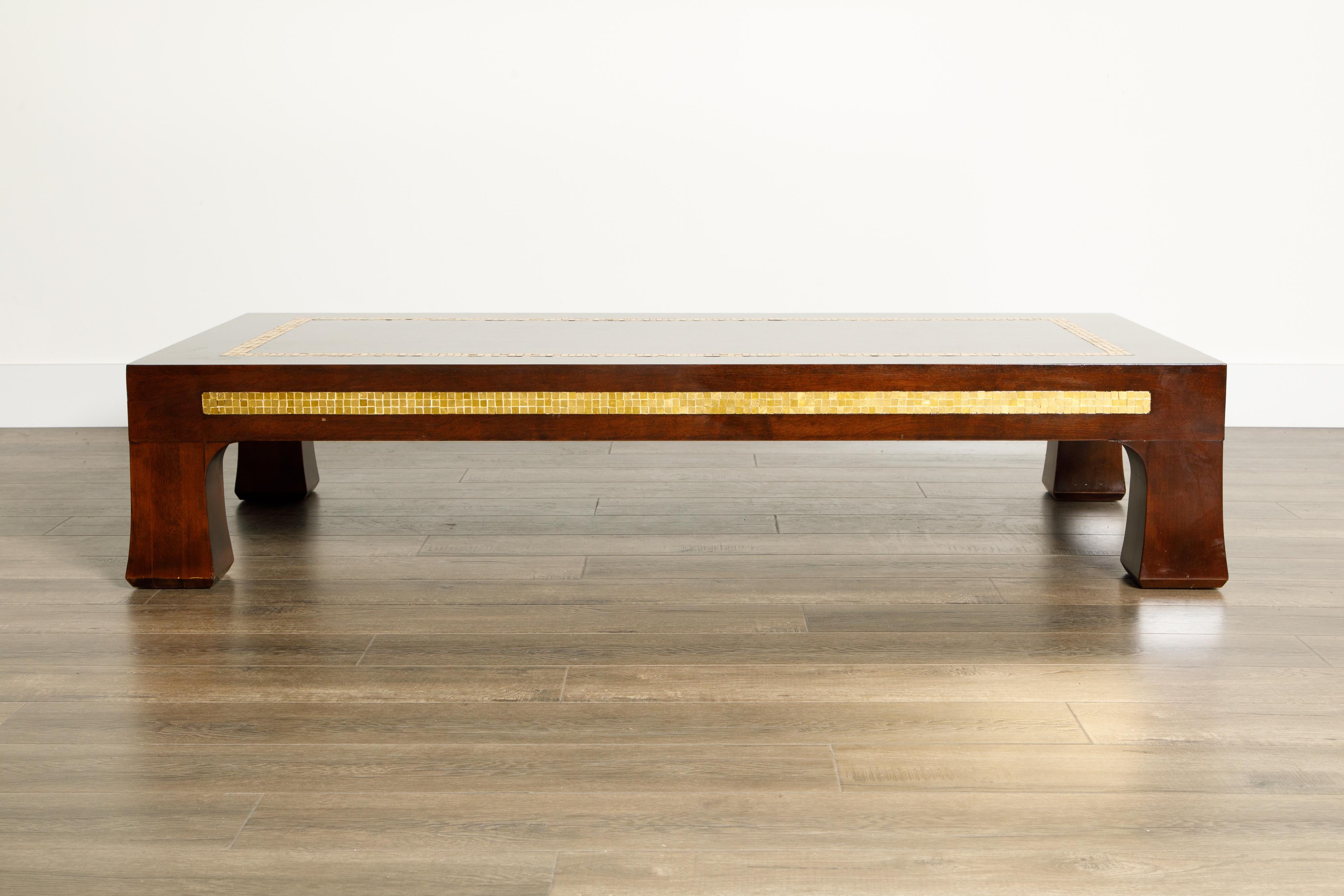 This spectacular deep brown walnut coffee table was designed by Edward Wormley for Dunbar, circa 1950s, and features Mid-Century Modern flared legs and golden mosaic tile inlay wrapping all four sides and on the table top. Signed underneath with the