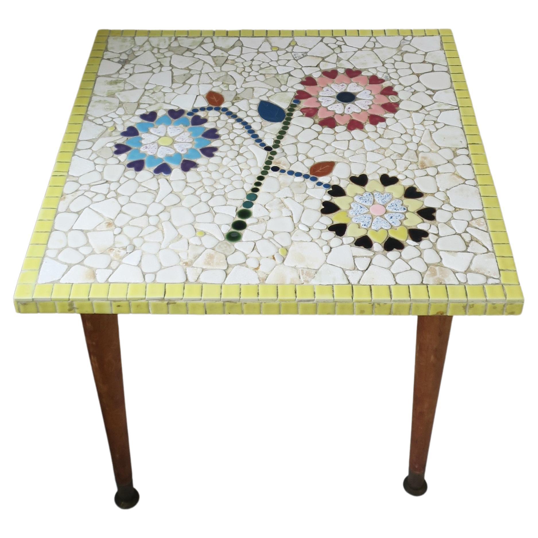 A hand-crafted Mid-Century Modern mosaic tile top end table, circa 1960s. Table is square with three flowers or sunflower-like design comprised of heart shaped tiles, background tiles are white in an organic form, finished with yellow square mosaics