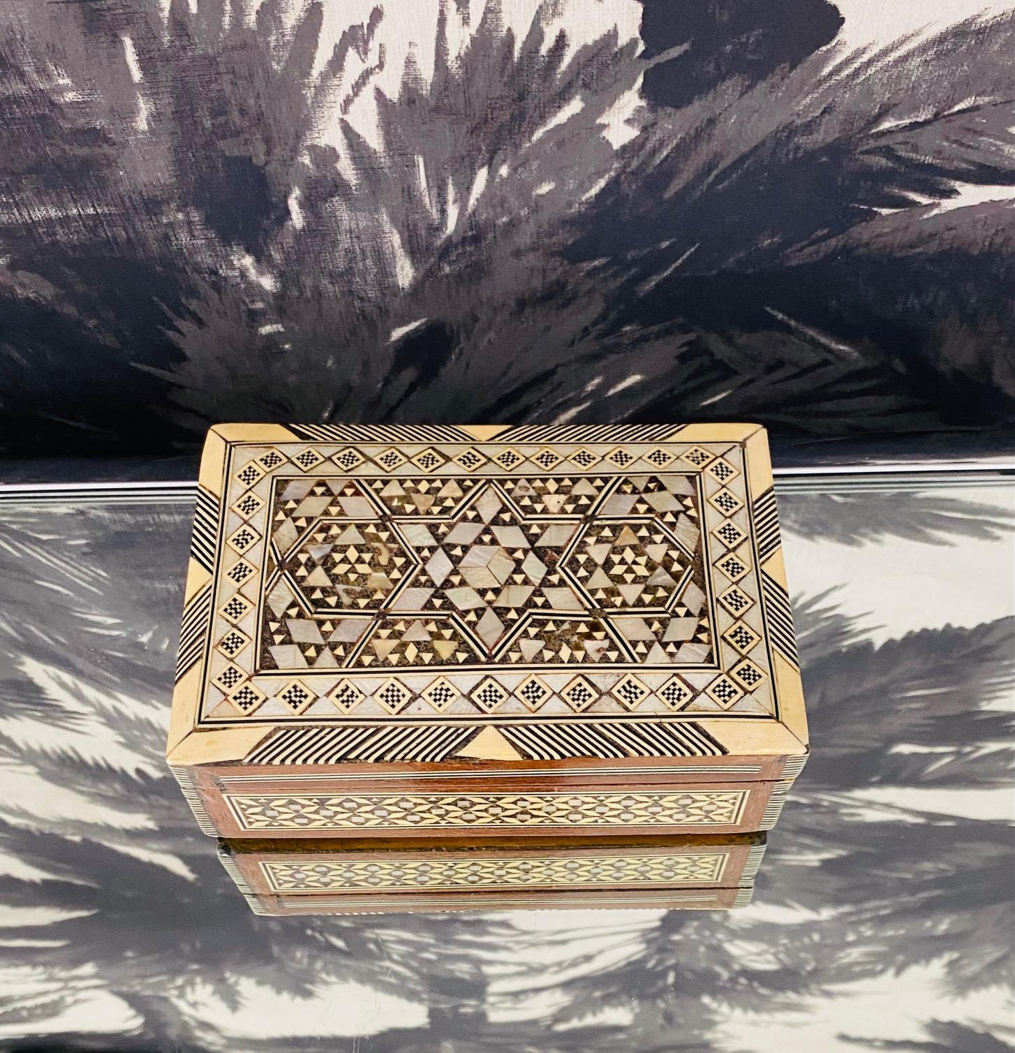 Exquisite handcrafted decorative wood box with mosaic marquetry design. Vintage Moorish style box features geometric inlays in mother of pearl and bone. Outstanding artisanal craftsmanship with hinged lid and interior lined in vibrant red velvet.