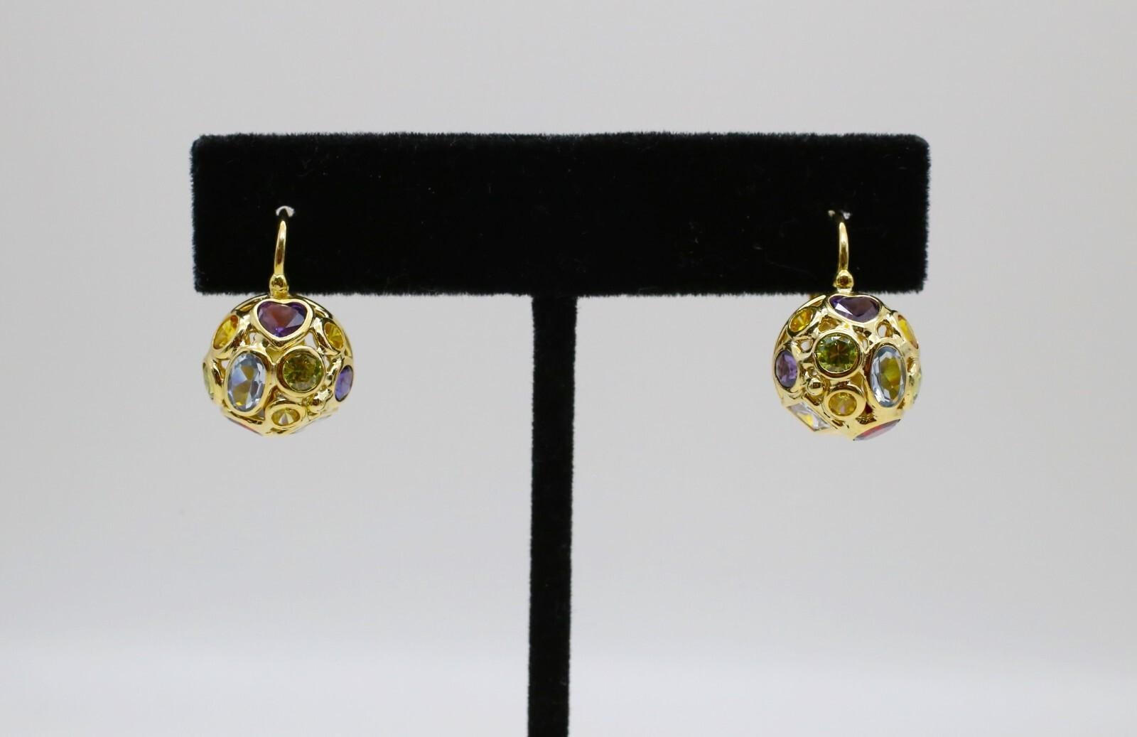 These vibrant 18k yellow gold earrings by Mosaico are a playful yet elegant celebration of color and craftsmanship. Each spherical drop is intricately openworked and inlaid with an array of bezel-set multicolored gemstones, including amethyst,