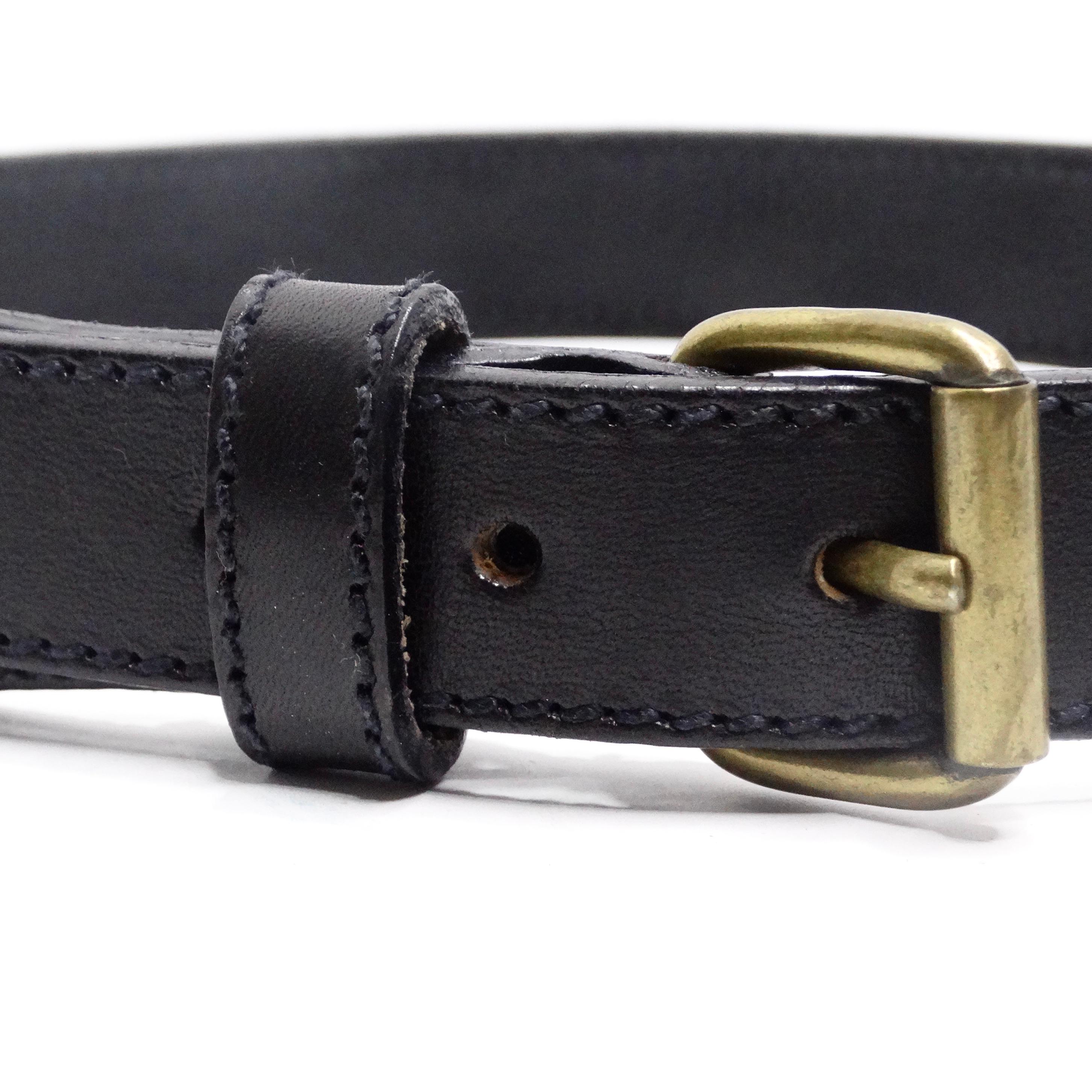 Rehaussez votre garde-robe avec la ceinture en cuir noir ornée de pièces de monnaie Moschino 1990 - un accessoire intemporel et polyvalent qui fusionne sans effort le charme vintage et le style contemporain. Cette ceinture en cuir noir est ornée de