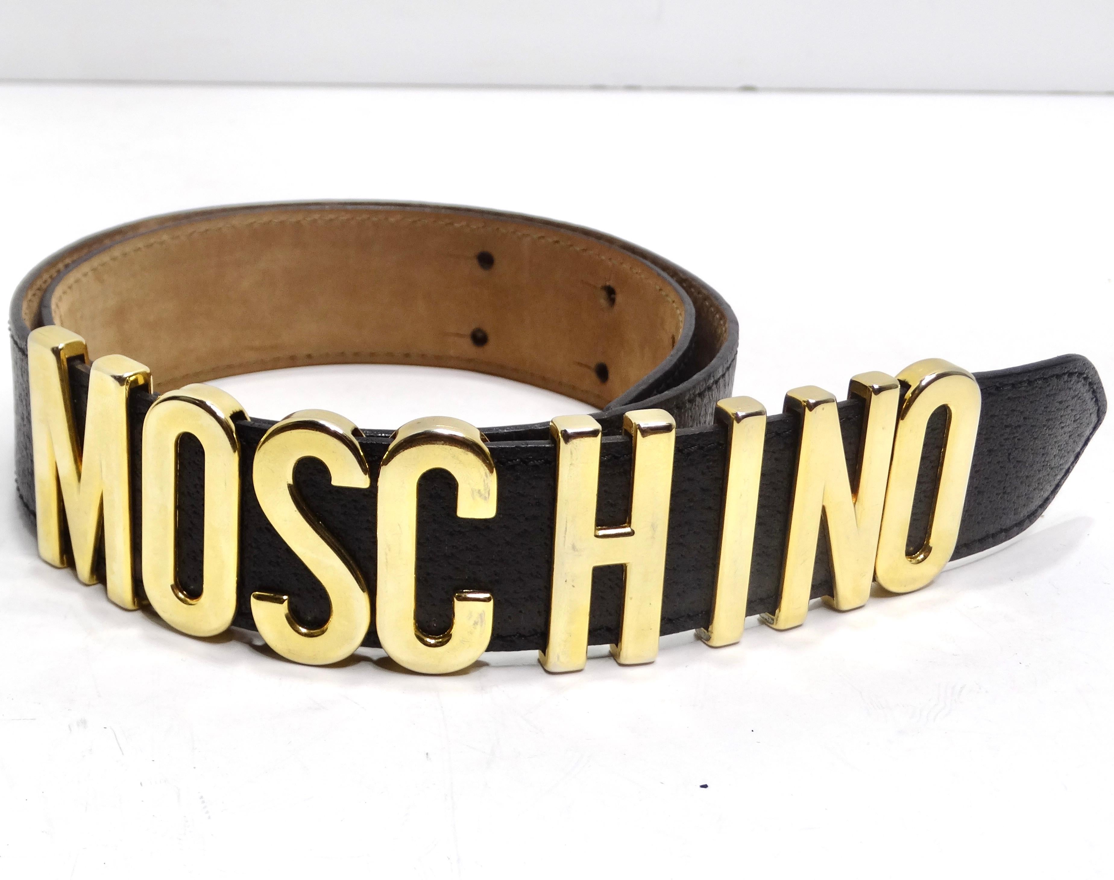 Setzen Sie ein mutiges Statement mit dem Moschino 1990s Gold Tone Logo Black Leather Belt - eine wahre Verkörperung des 90er Jahre Glamours und des unverwechselbaren Moschino Stils. Dieser schwarze Ledergürtel ist mit einem großen, auffälligen,