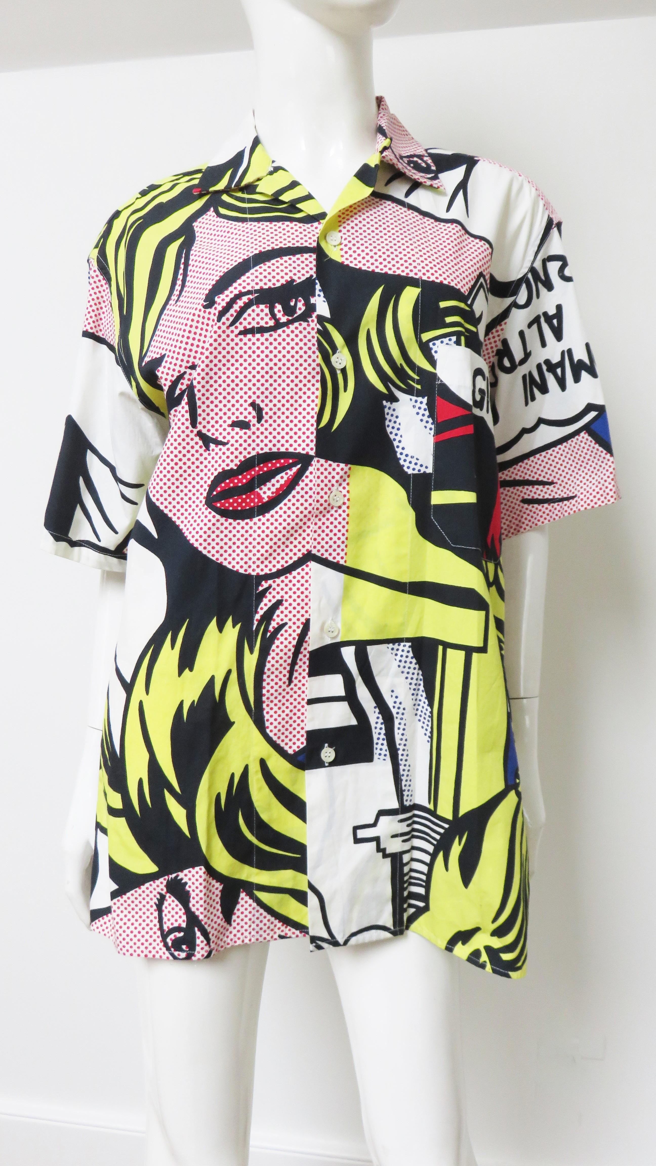 A fabulous white cotton shirt with a Lichtenstein comic book print in bright primary colors from Moschino Cheap and Chic Uomo.  It has a shirt collar, short sleeves, a breast pocket and is resplendent with a woman's face and Italian words and