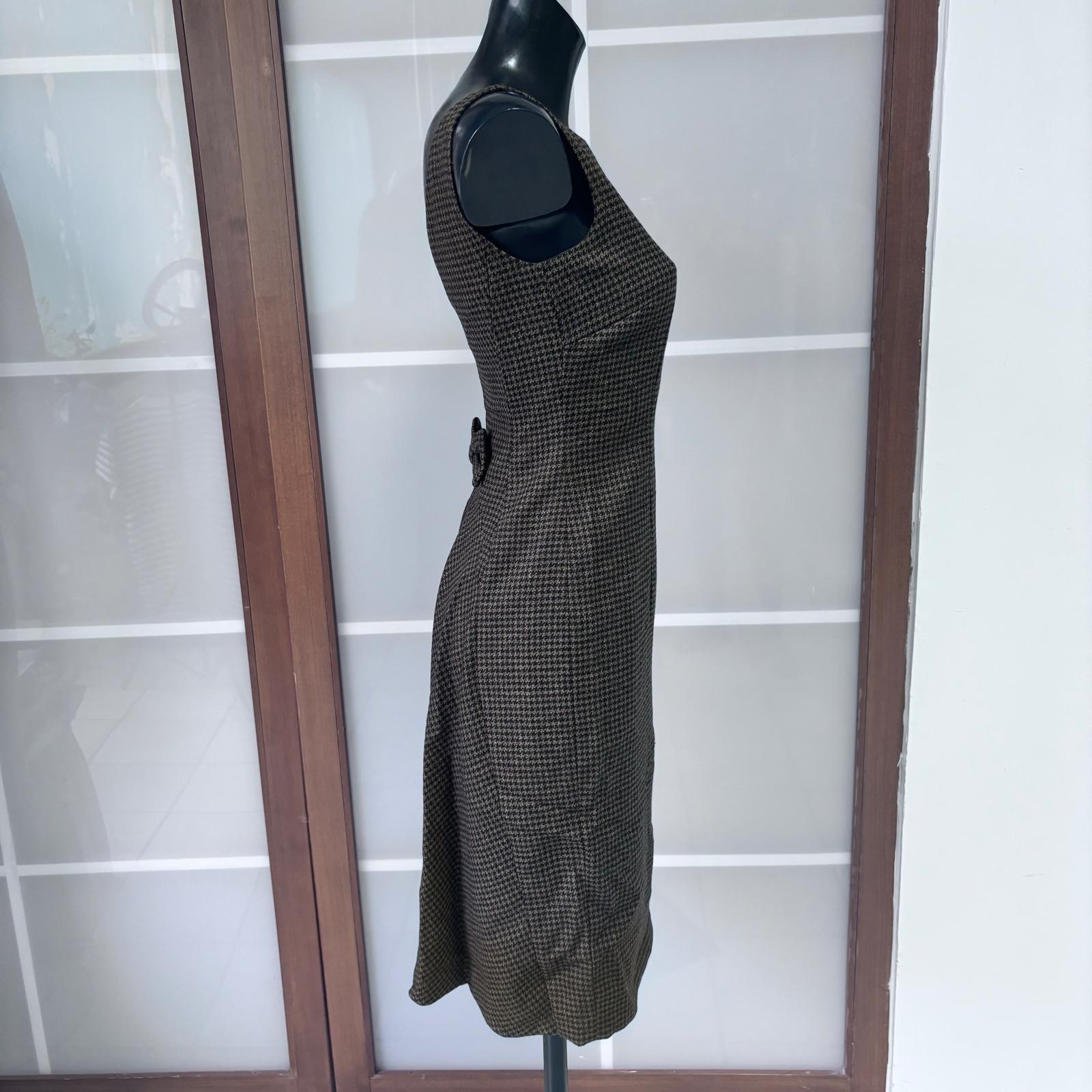 Elegantes Moschino Etuikleid, hergestellt in Italien in den 1990er Jahren, aus feinem Wollstoff mit einem Prince of Wales-Muster in Braun- und Beigetönen.
Das Modell ist ärmellos, hat einen geraden Ausschnitt und eine taillierte Linie, die die