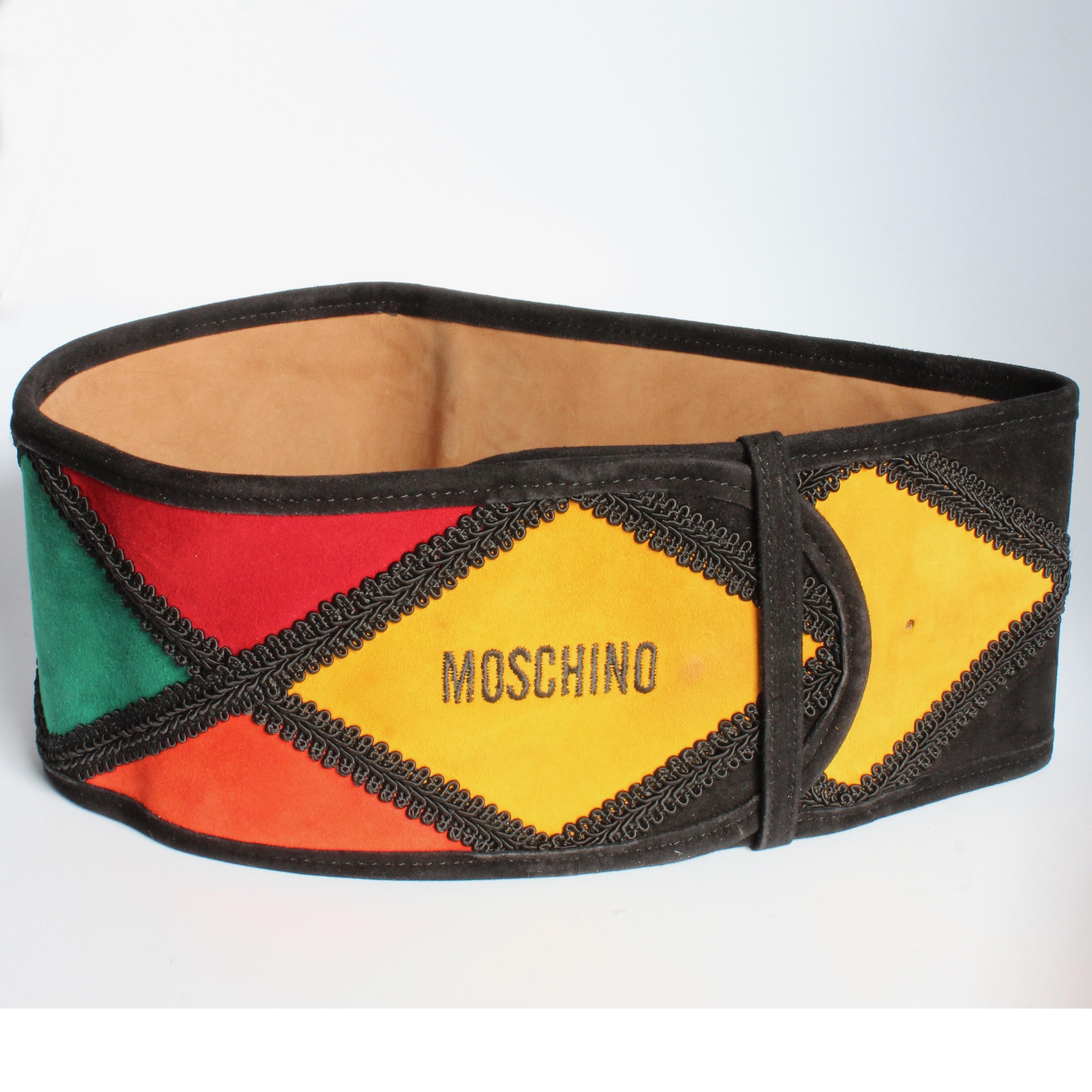 Here's an incredible wide suede leather belt, made by Moschino by Redwall Italy, most likely in the 1980s. Made from colorful harlequin suede patches, it fastens with a hidden hook and is backed in tan leather. 

An extra wide and over-the-top belt