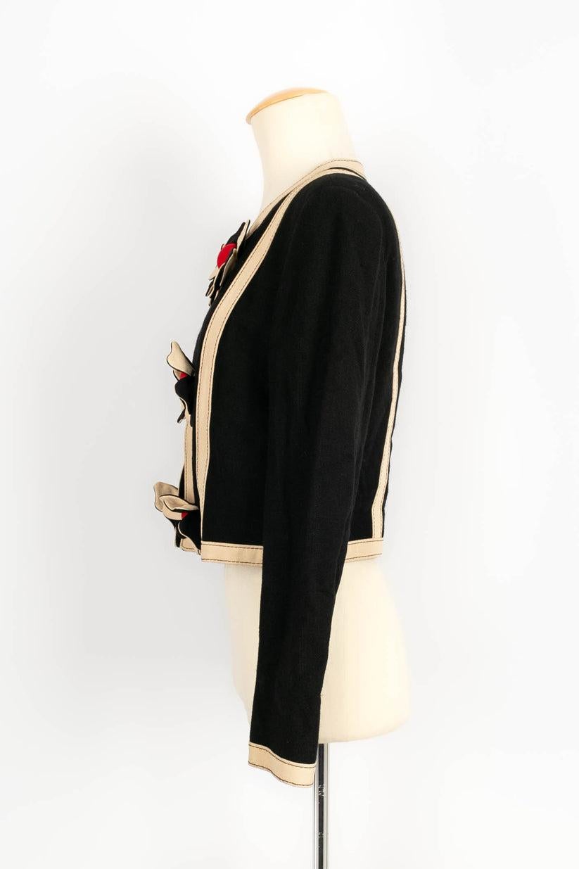 Moschino -(Made in Italy) Black and beige short jacket decorated with two rows of flowers. No size indicated, it fits a 34FR.

Additional information: 
Dimensions: Shoulder width: 39 cm, Sleeve length: 58 cm, Length: 43.5 cm
Condition: Very good