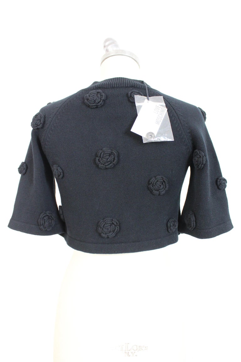 Moschino 2000s women's jacket. Short cardigan at the waist, black with applied flowers. Short sleeve, clip button closure. 100% cotton fabric.

Condition: New with tag

The item is new, it comes from the shop with its original tags.

Size: 40 It 6