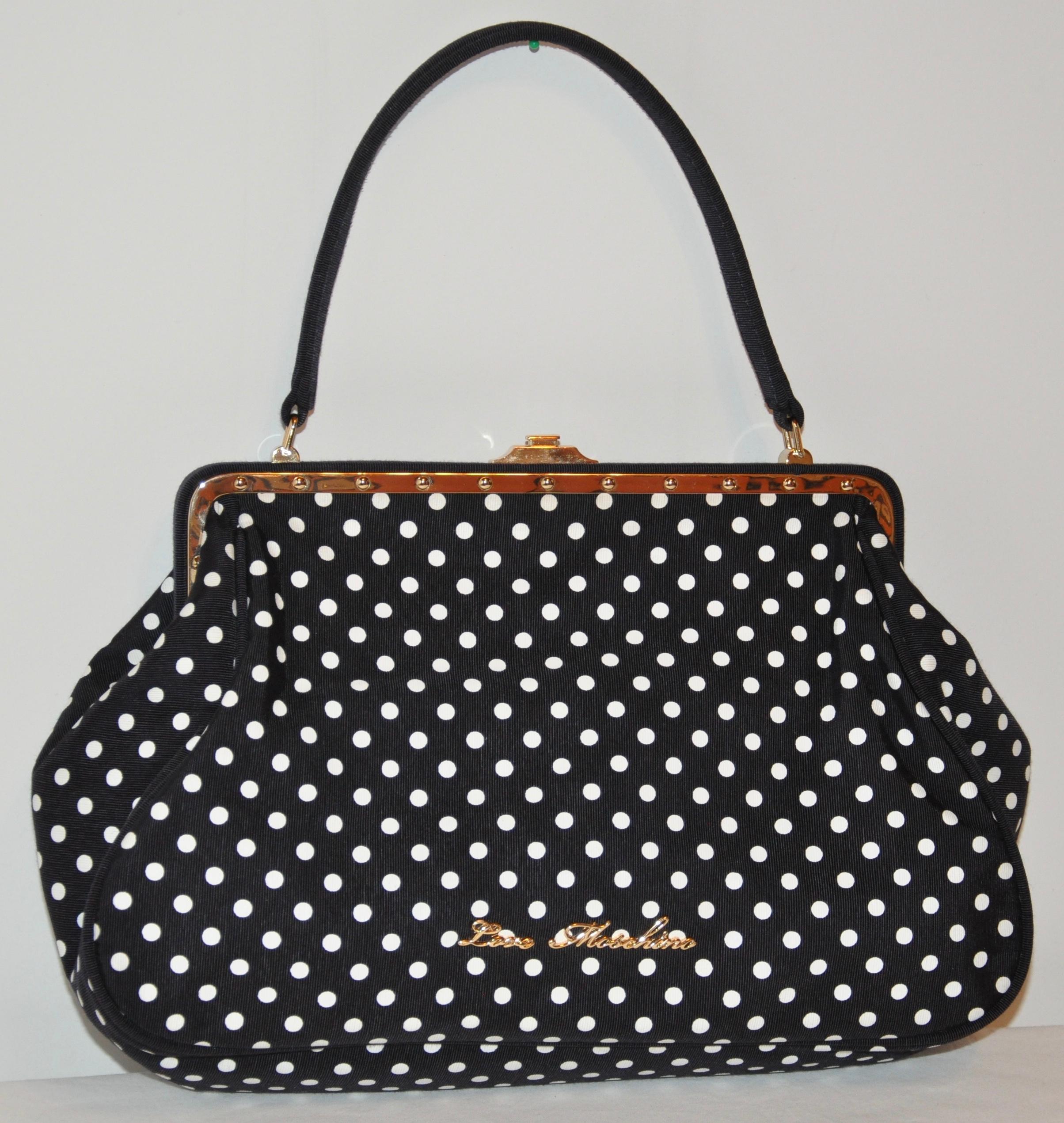 Moschino wonderfully elegant yet whimsical textured black with white polka dot silk handbag is accented with a polished gilded gold hardware frame. The opening on top is a 