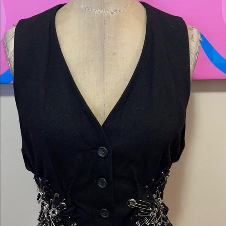 Moschino black wool safety pin vest

This wool vest is a show stopper with unique gathered details and safety pins. Pair with black pencil pants or pencil skirt over a long sleeve white blouse for a finished look. 
Size 8
Across chest - 18.5