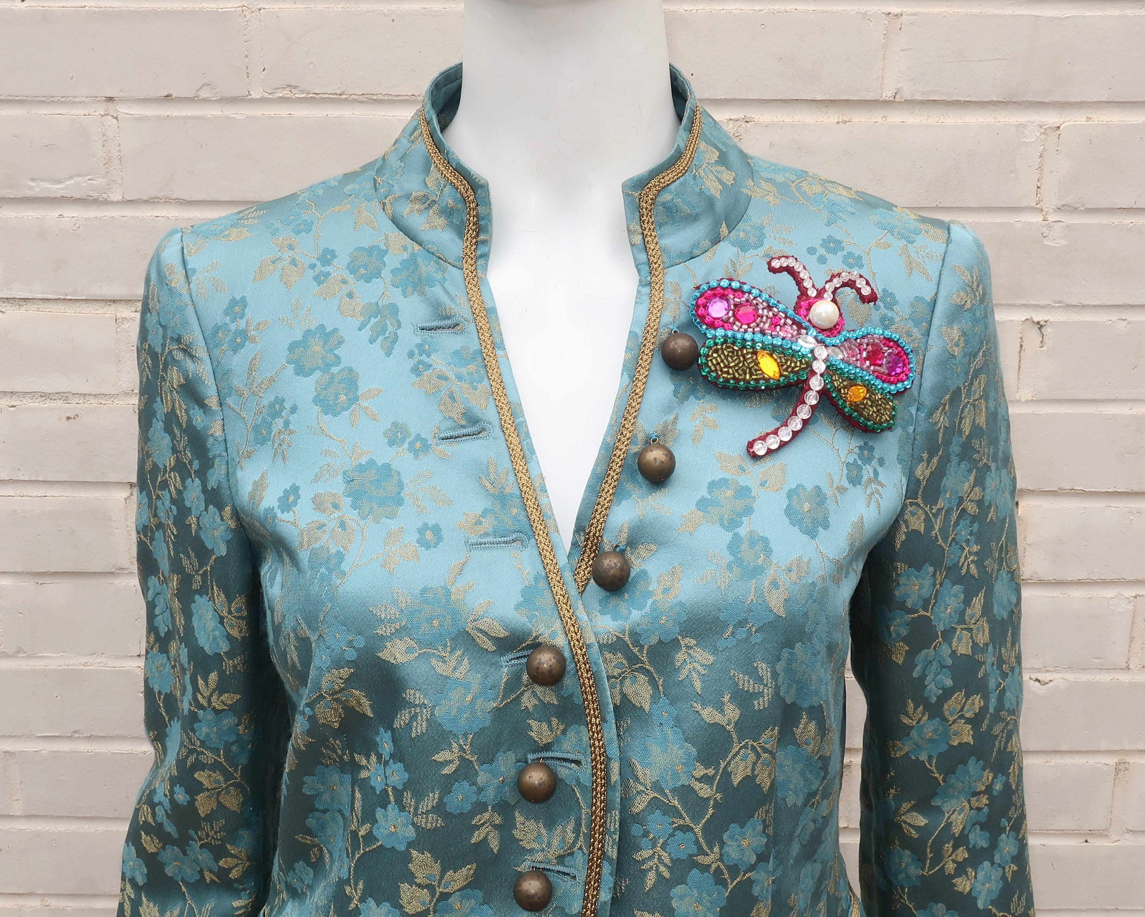A whimsical ‘I Love Bollywood’ light teal green and gold brocade jacket from Moschino's Cheap And Chic label trimmed in an antique gold braid and accented by a brightly colored jeweled dragonfly introducing shades of fuchsia, red, gold, green, aqua