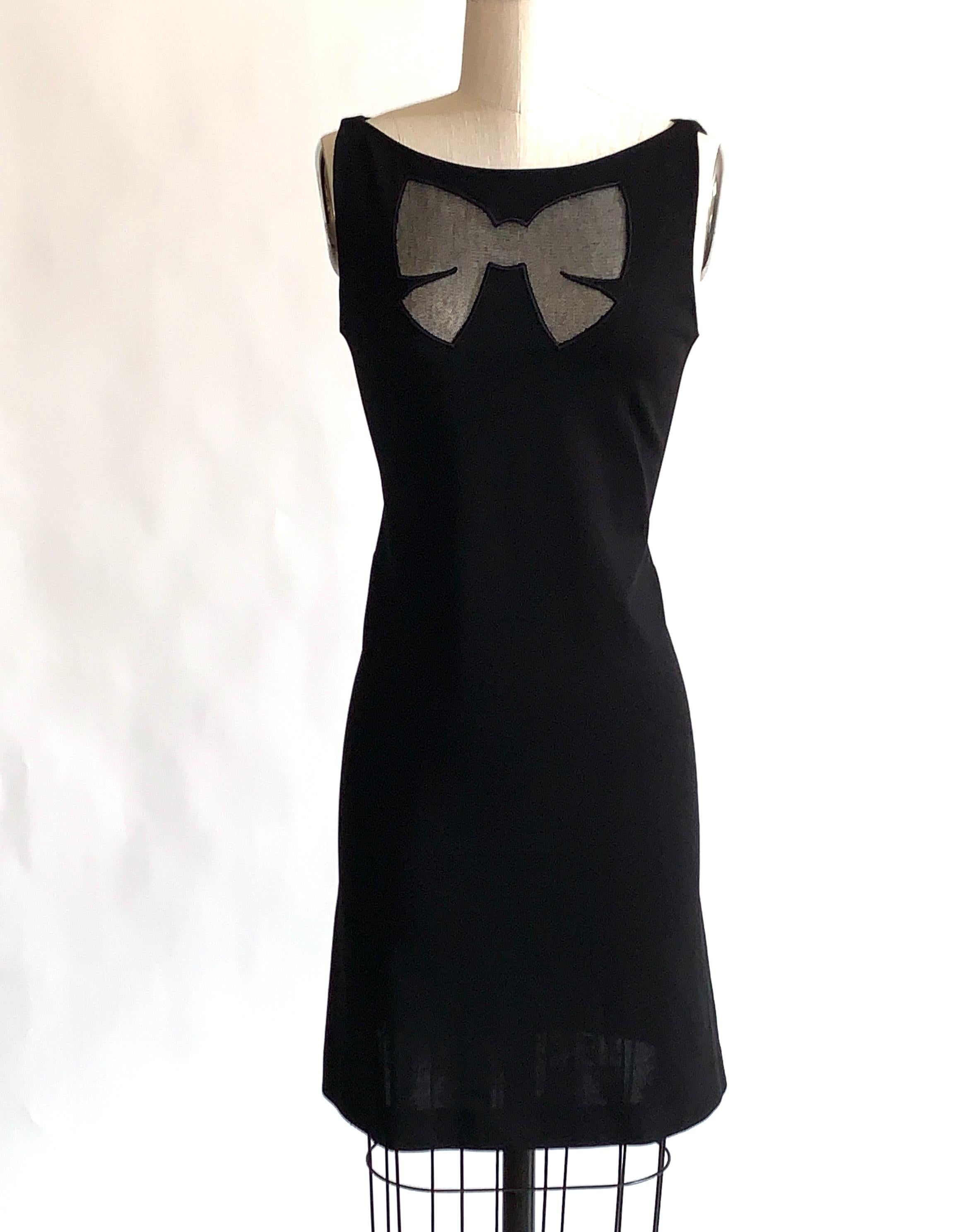 Vestido de punto negro sin mangas de los años 2000 Moschino Cheap and Chic con forma de lazo recortado en el pecho de malla negra. Cremallera dorsal.

86% rayón, 9% poliamida, 5% otros.
Sin forro.

Fabricado en Hungría.

Etiquetada como talla IT 42,