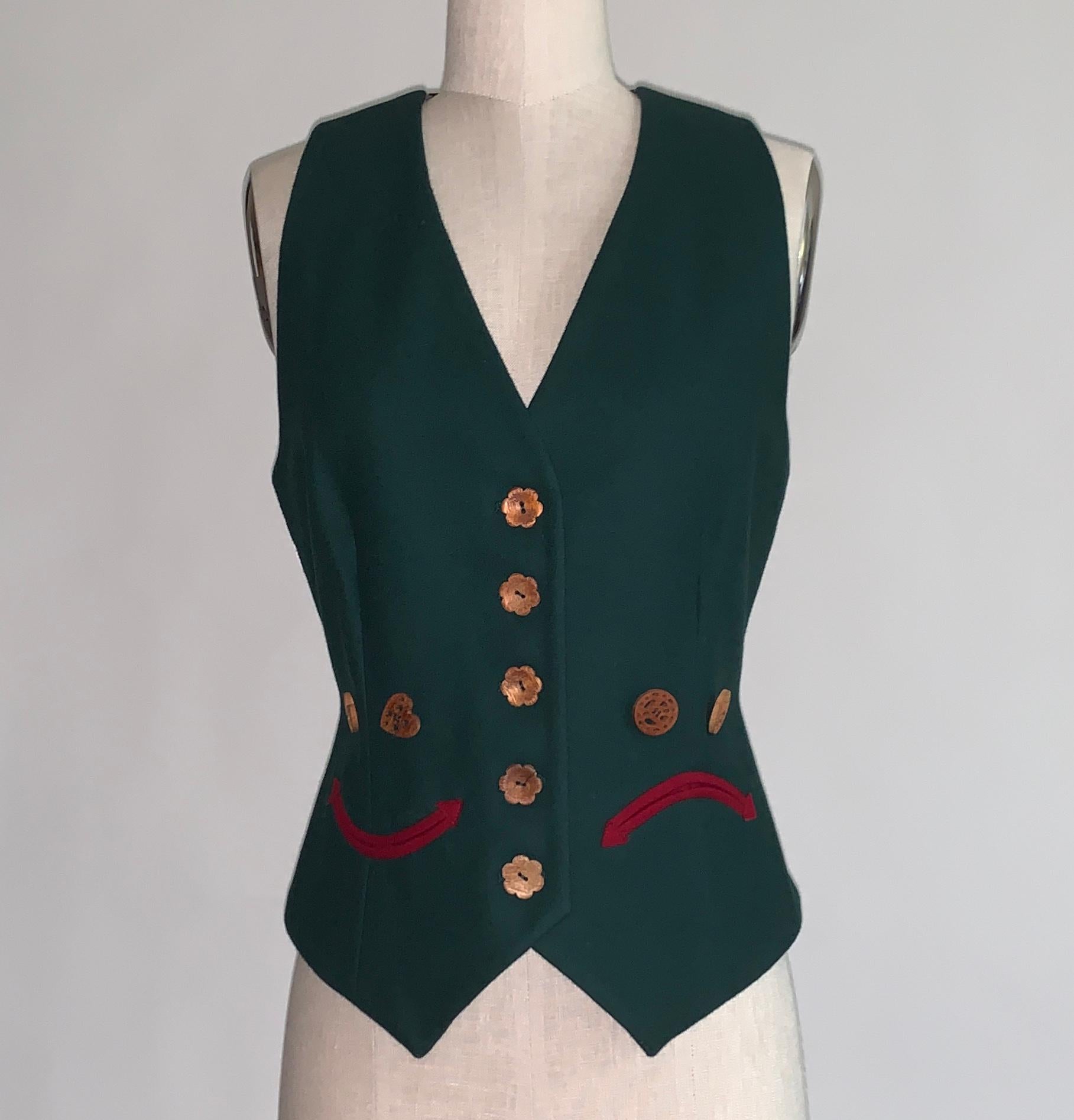 Vintage Moschino Cheap & Chic 1990s green vest featuring a happy face on one side and a sad face on the other. (Moschino was way ahead on emoji style!) Red trim creates the mouths while wooden buttons with cut out details (heart on smiley side,