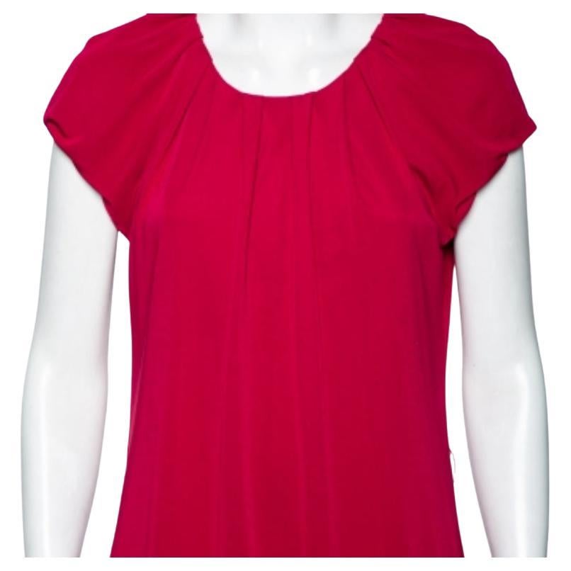 Este vestido de la Casa Moschino Cheap and Chic añadirá un toque intrincado a tu conjunto. Está confeccionado en tejido de punto fucsia, con un detalle de yema plisada que eleva su silueta. Tiene mangas cortas. Combina este vestido con accesorios