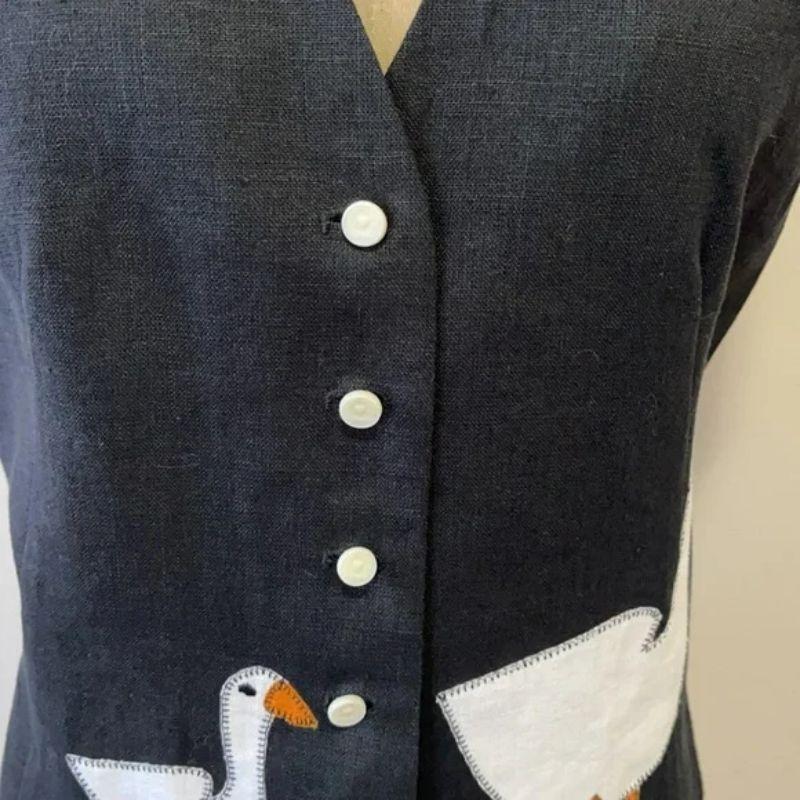 Moschino billig chic Leinen Ente Weste

Mit dieser einzigartigen Vintage-Weste von Moschino Cheap and Chic mit einem lustigen Entenmotiv auf der Vorderseite sind Sie retro-cool. Kombinieren Sie dazu eine schwarze Hose und ein langärmeliges weißes