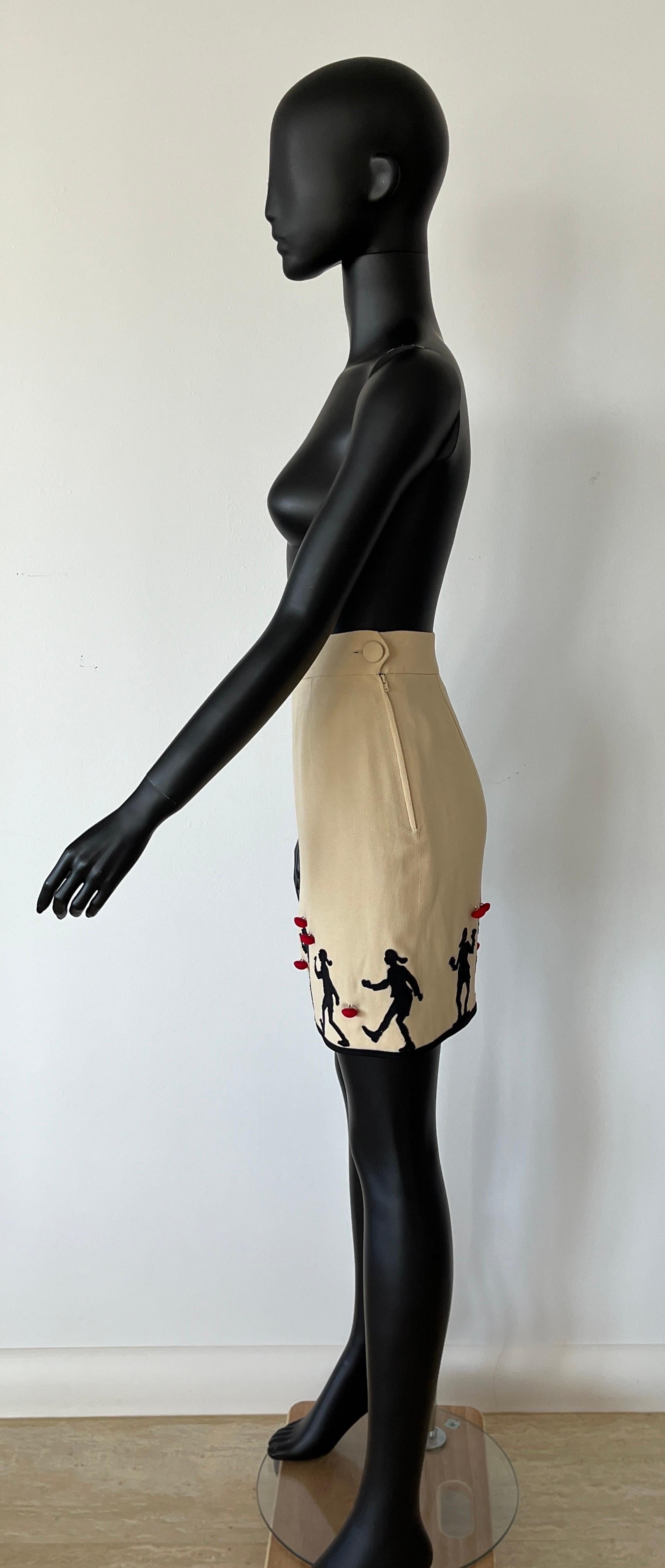 Iconic and collectable Moschino Cheap & Chic cream skirt features OLIVE OIL FROM POPEYE appliquéd on front and back entire hemline, with red self covered buttons. 
A fantastic example of 1980's Moschino!

Fully lined, side zip closure and self