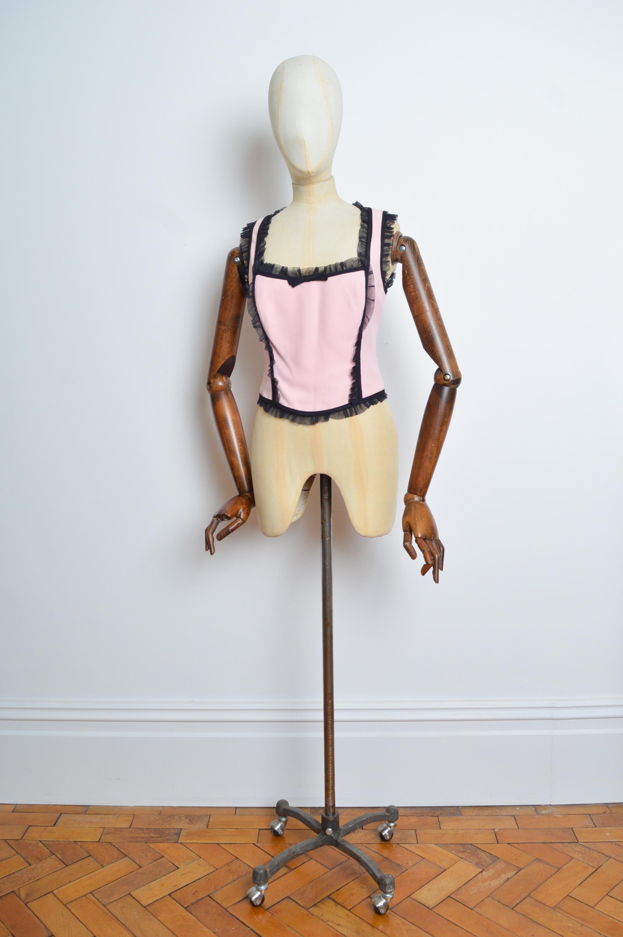 MOSCHINO billig & schick Pastellrosa & Schwarz Coquette Bustier - Korsett-Oberteil
Eigenschaften - Schwarze Rüschen aus Mesh, Schleife auf der Vorderseite, eckiger Kragen, verdeckter Reißverschluss auf der Rückseite und vollständig gefüttertes