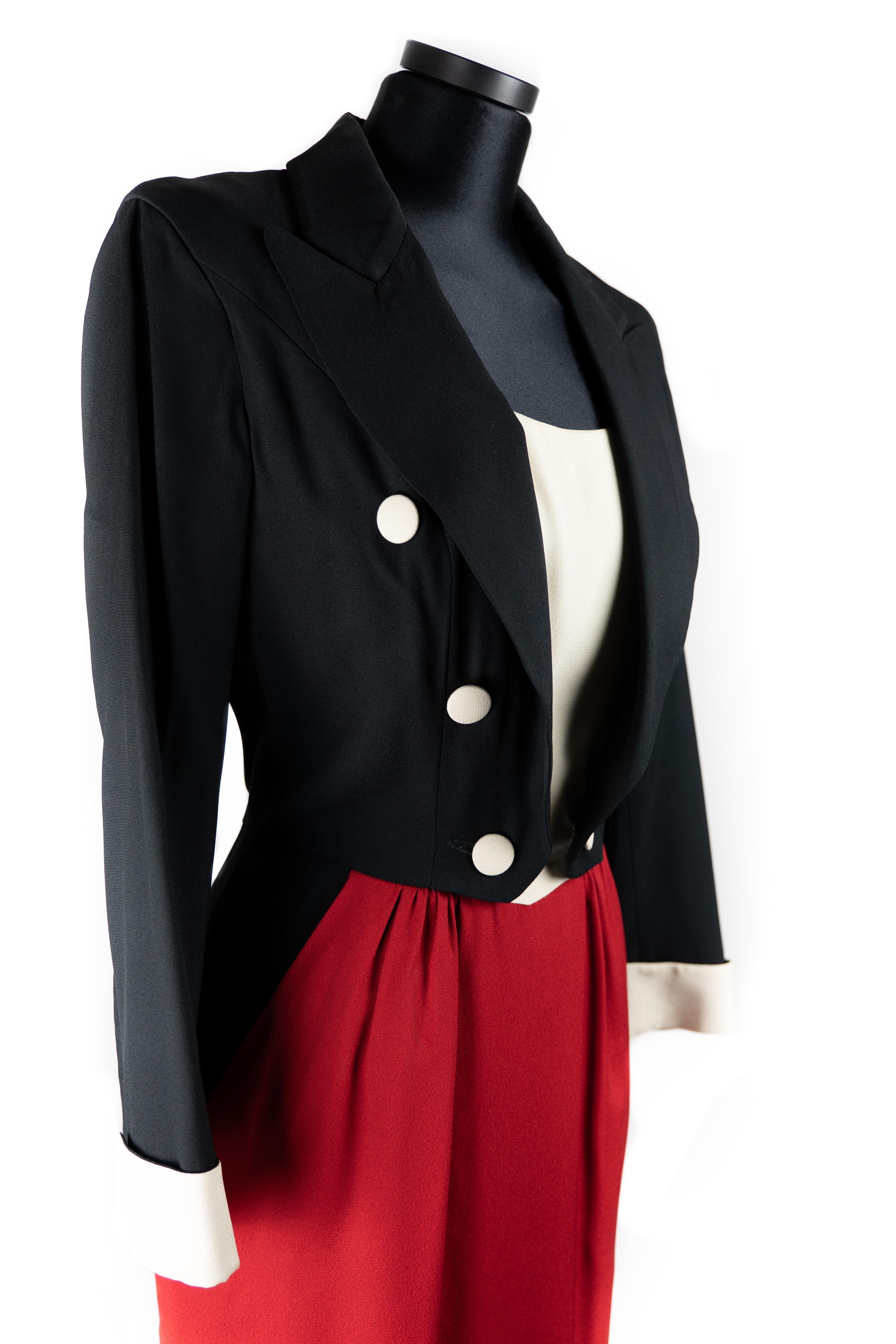 Moschino Cheap And Chic Tuxedo Dress. Circa 1990s.
Featuring black double breast jacket, long sleeves and fold cuffs matching white top and buttons. The straight skirt presents pockets, a back vent, and the appearance of jacket tails in the back. It