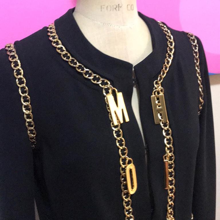 Moschino couture black gold chain charm jacket

Unique jacket with gold chains and metal charms that spell Moschino down the front - pair with black skinny pants and ankle boots for a great look. Hook and eye closures. 
NOTE:  The gold on the chain