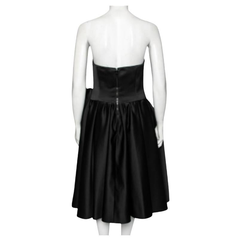How pretty and feminine is this dress from the House of Moschino Couture! Draped elegantly using black satin fabric, this dress is accentuated with pleated formations and a bow motif on the front. It is equipped with a zip-type fastening. Wear this