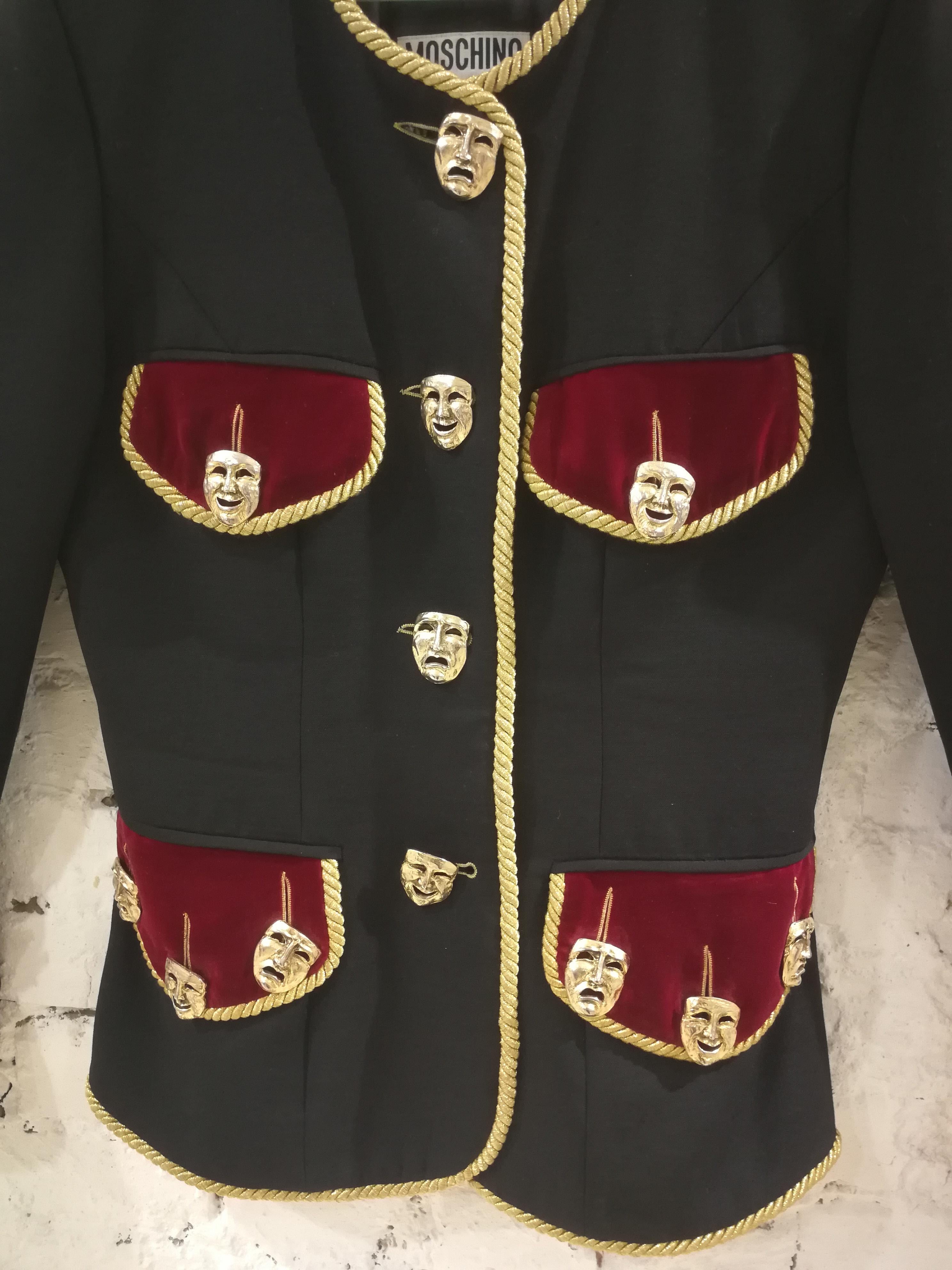 Moschino Couture Black Wool Masks Jacket
Black Moschino Couture vintage wool military jacket with gold-tone Comedy and Tragedy mask button accents throughout, burgundy velvet trim at cuffs and four front flap pockets, gold-tone braided trim
