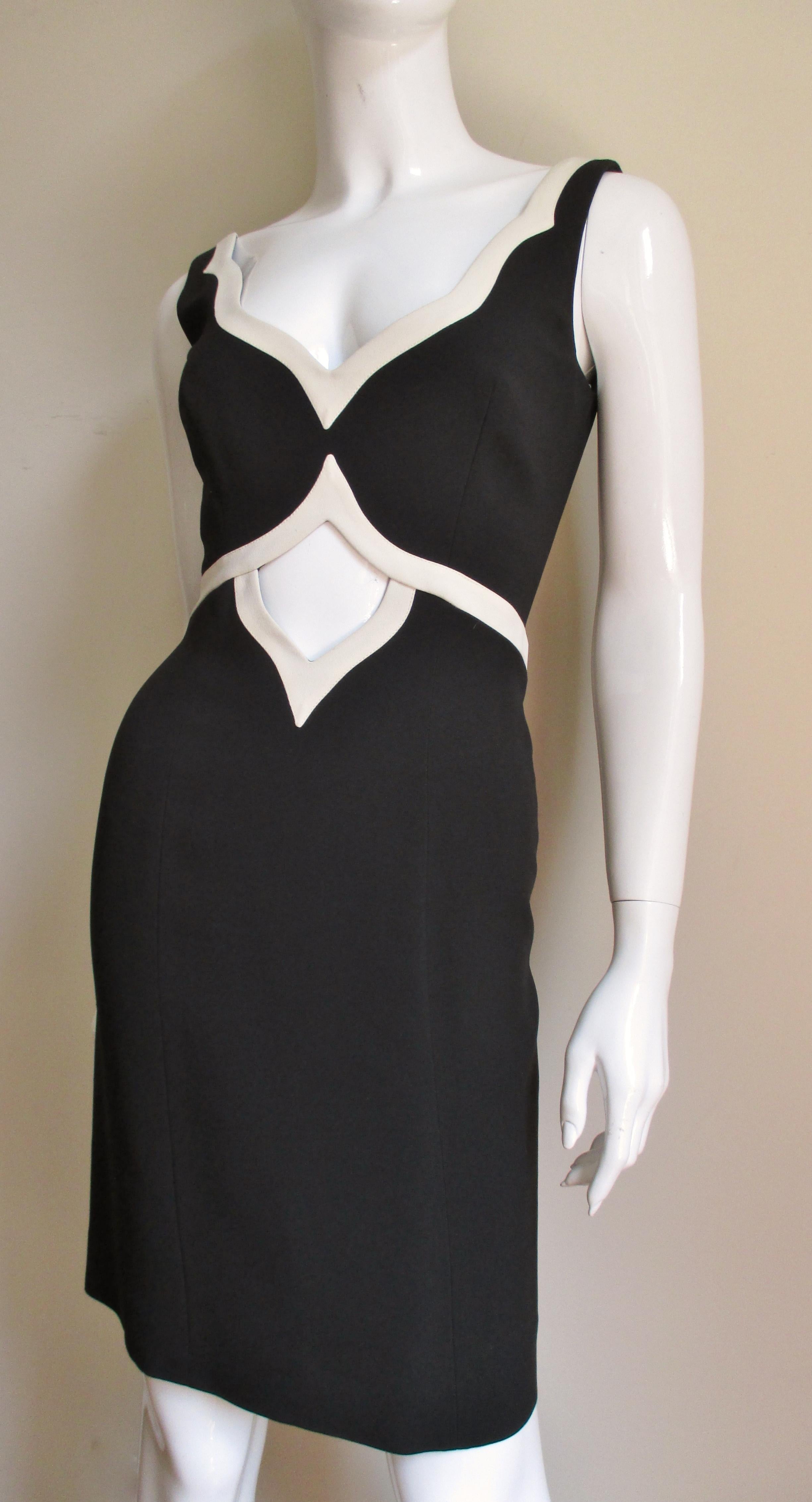 A fabulous dress from Moschino Couture in black with off white trim.  It is sleeveless with a V neckline, a waist cut out below it and a low cut back, all trimmed in off white. The dress has a back invisible zipper and is fully lined. 
Fits sizes
