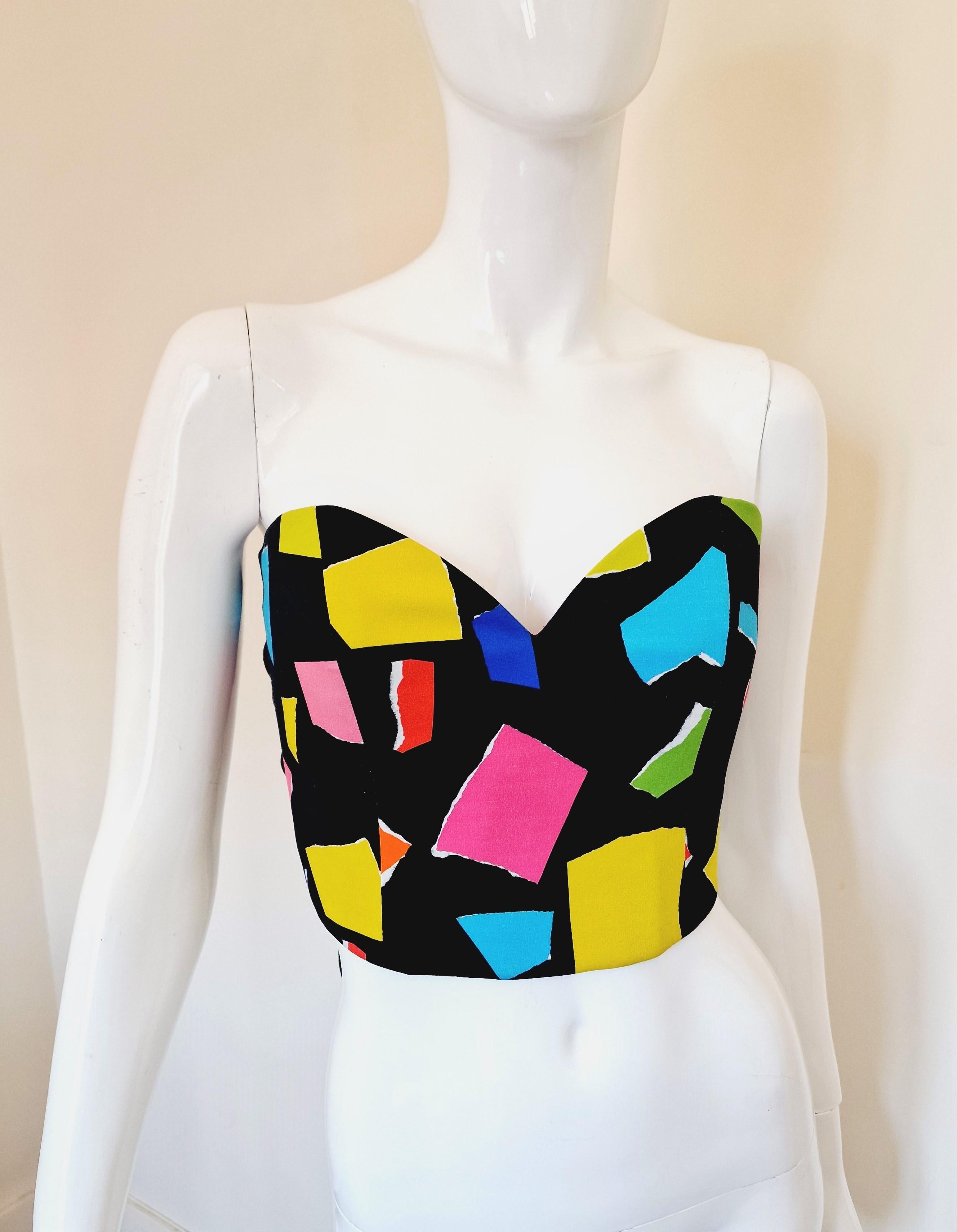 Moschino Couture structured bustier with boning and adjustable bow tie at back.
Designed by Jeremy Scott.
Black and multicolor abstract print with sweetheart neckline and tie back. 
Boned at front.
Fastens at back with cloth covered elastic on