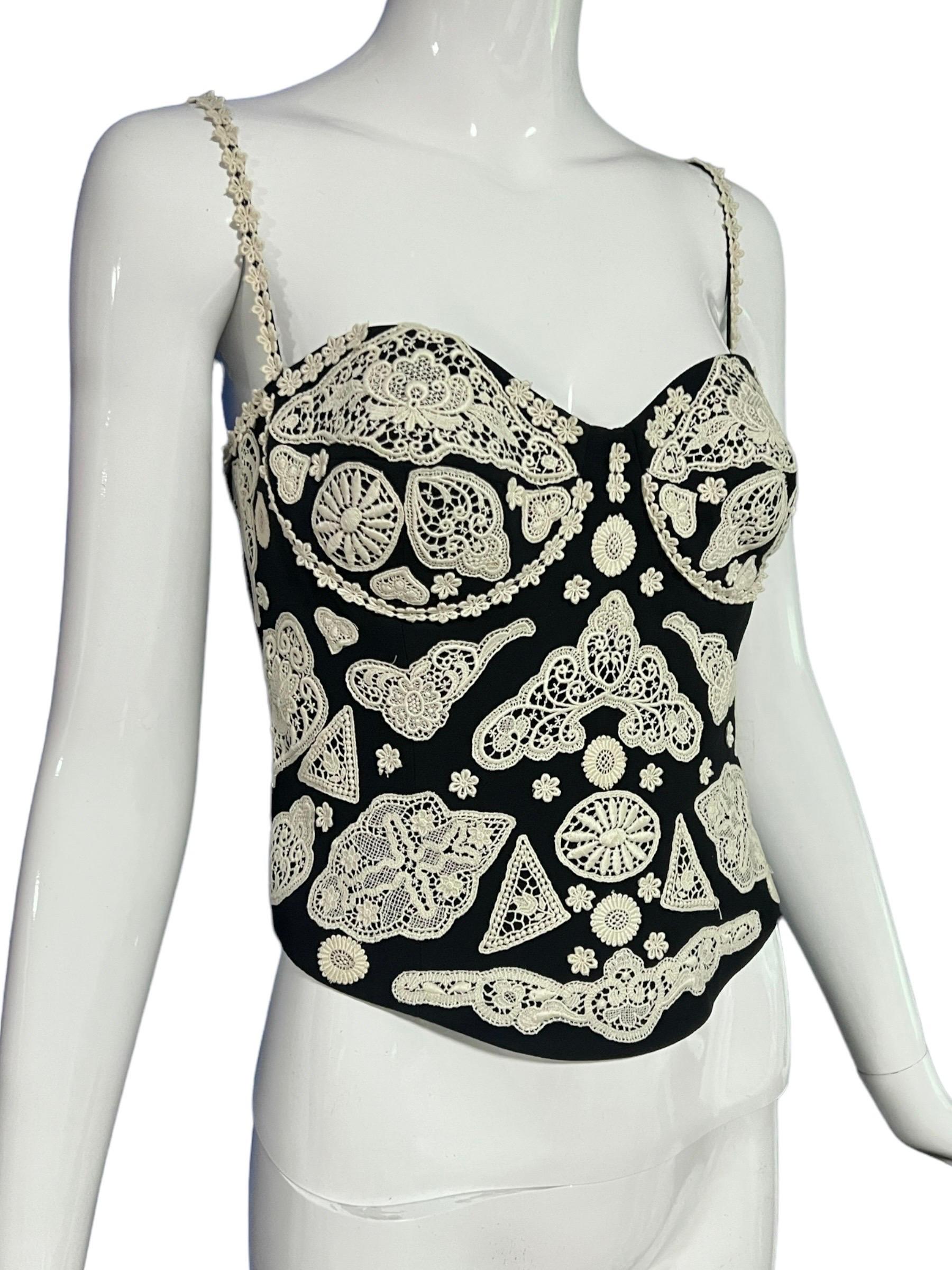 Corpiño negro Moschino Couture vintage de los años 90 con apliques de encaje de ganchillo en blanco roto. 
Este top tiene una superposición de encaje, tirantes bordados y una cremallera lateral.

Talla: Talla US 12.

Estado: Excelente estado en