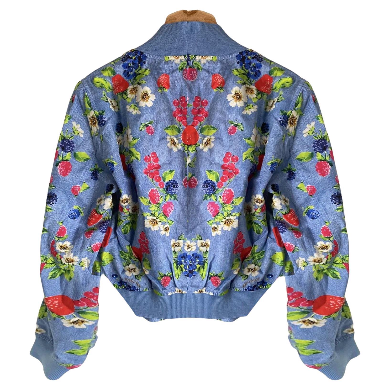 Crafted from a polyester material with a denim-like texture, this Moschino bomber jacket features a vibrant fruit pattern on its blue background. An elastic waist and collar, full zip closure, and two front pockets complete the design. It is