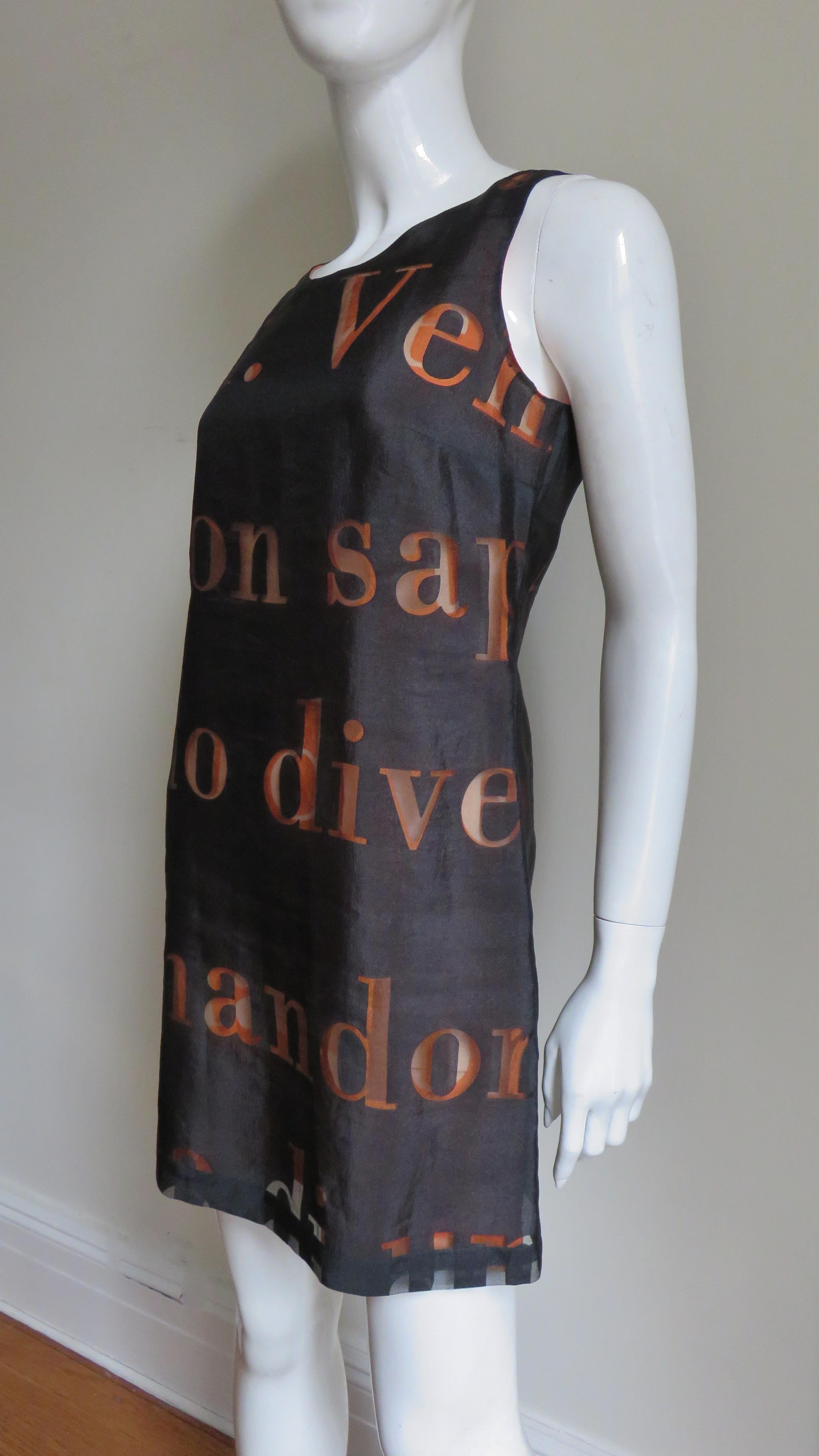 A fabulous semi sheer black dress lined in orange with a letter pattern from Moschino.   It is a sleeveless semi fitted A line dress with a scoop neckline.  The dress is lined in orange and has a back zipper.
Fits sizes Small, Medium. US size