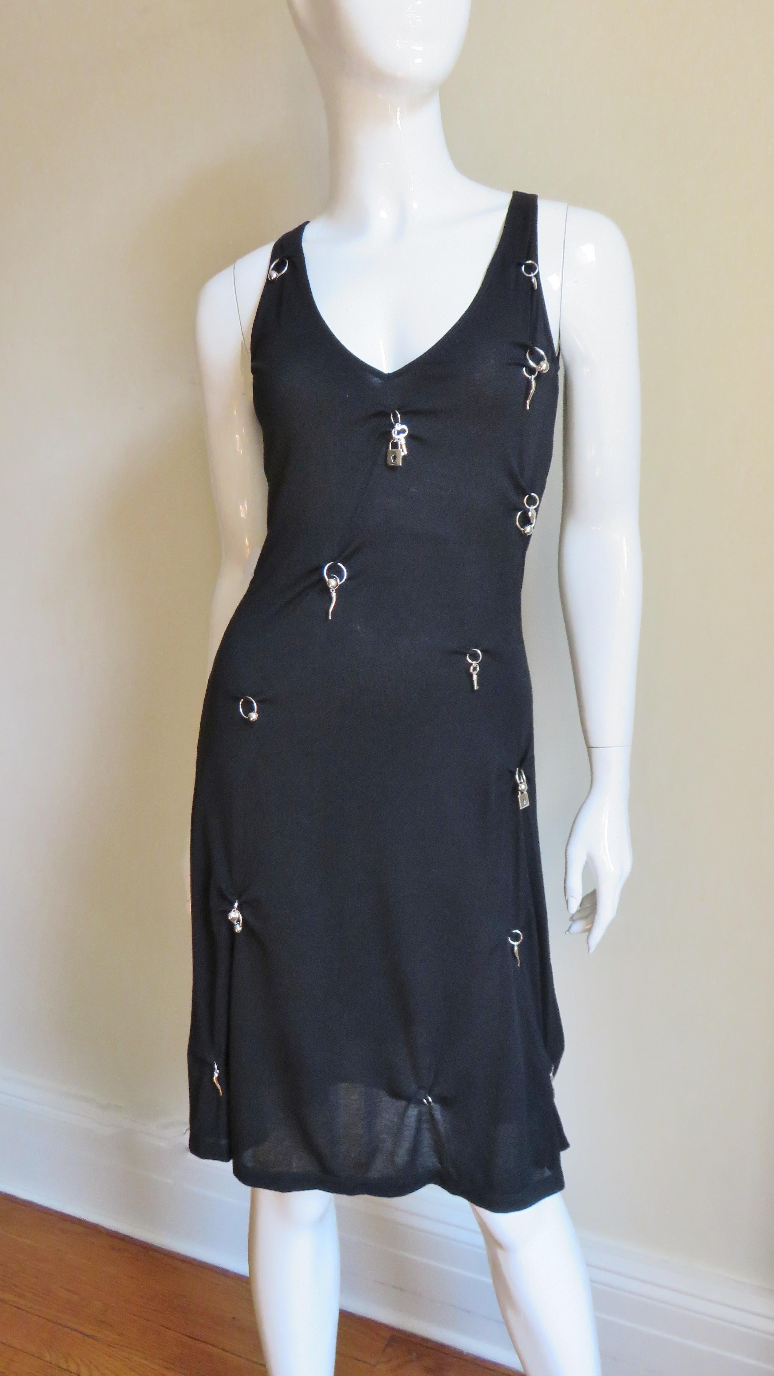A great black knit dress from Moschino with scattered silver metal charm keys, locks and hearts on the front.  The V neck dress is simple, fitted to waist then flaring to the hem. It is unlined.
Fits sizes Extra Small, Small, Medium.

Bust 