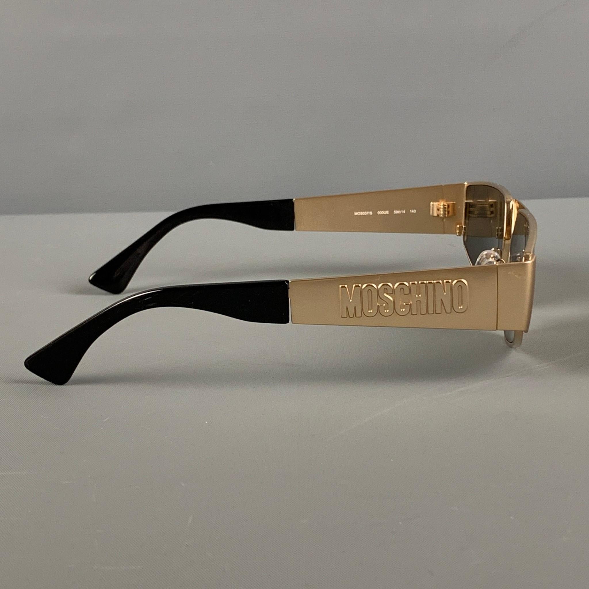 MOSCHINO sunglasses comes in a gold tone metal featuring a engraved logo design and tinted lenses. Includes case. 

Very Good Pre-Owned Condition.
Marked: MOS037/S  000UE 59-14 140

Measurements:

Length: 14.5 cm.
Height: 3.5 cm. 