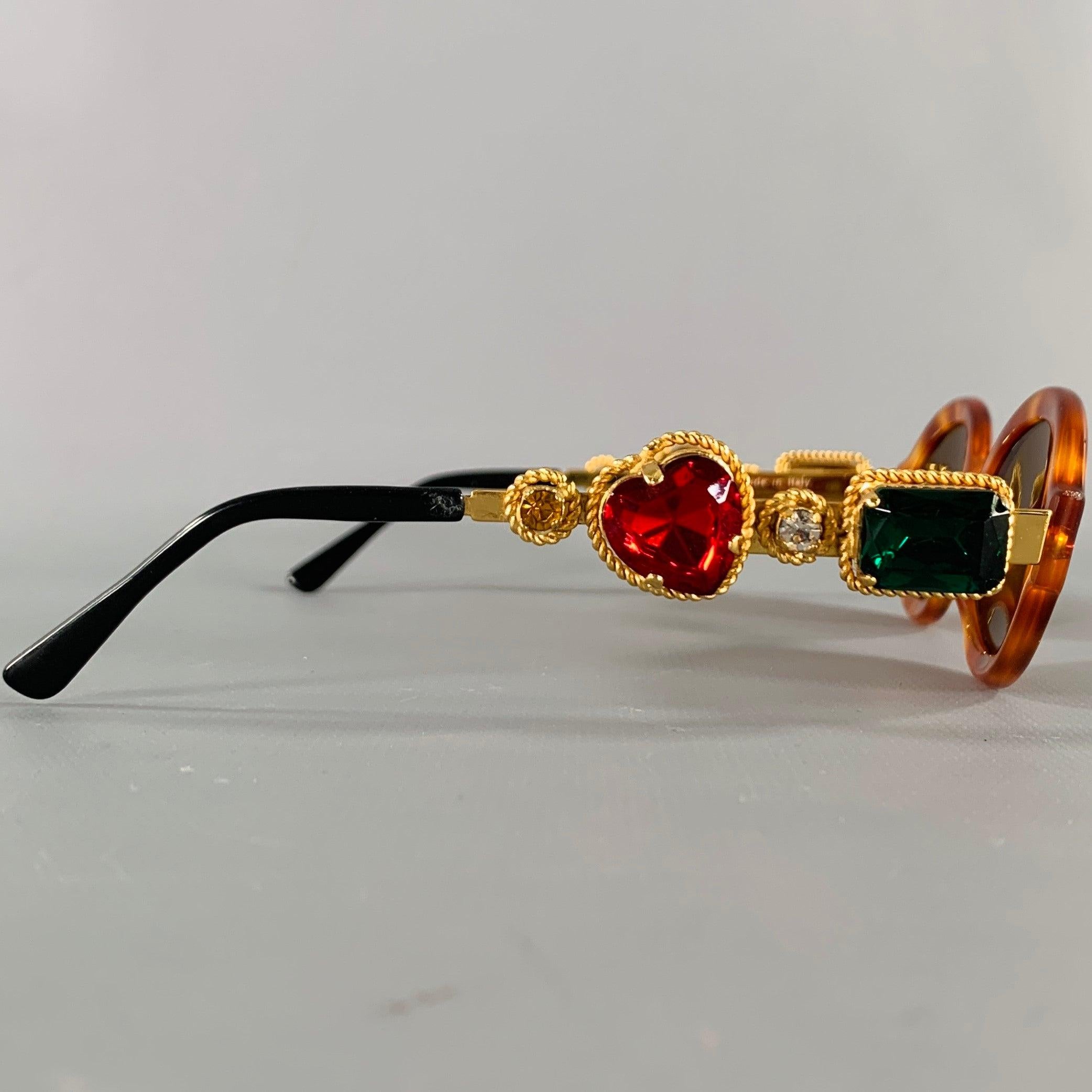 MOSCHINO by PERSOL sunglasses
in a brown tortoiseshell acetate featuring gold tone temple arms with red and green rhinestones.Very Good Pre-Owned Condition. 

Marked:   M268 

Measurements: 
  Frame Width: 14.5 cm.Frame Height: 4 cm.
  
  
 
Sui