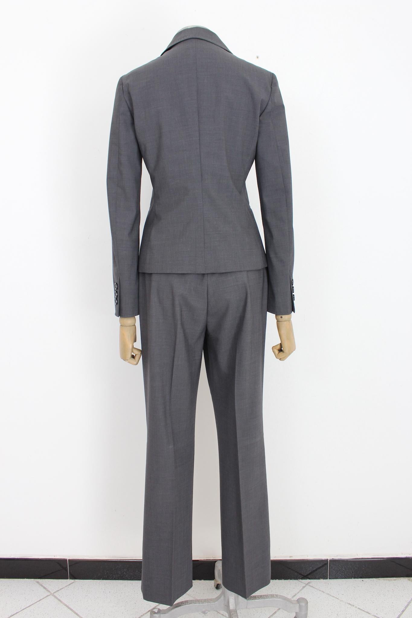 Costume pantalon classique Moschino pas cher et chic des années 2000. Veste modèle slim avec nœuds sur le col, pantalon classique à jambes droites. Couleur grise, tissu 95% laine, 5% autres fibres. Fabriquées en Italie.

Taille : 42 It 8 Us 10