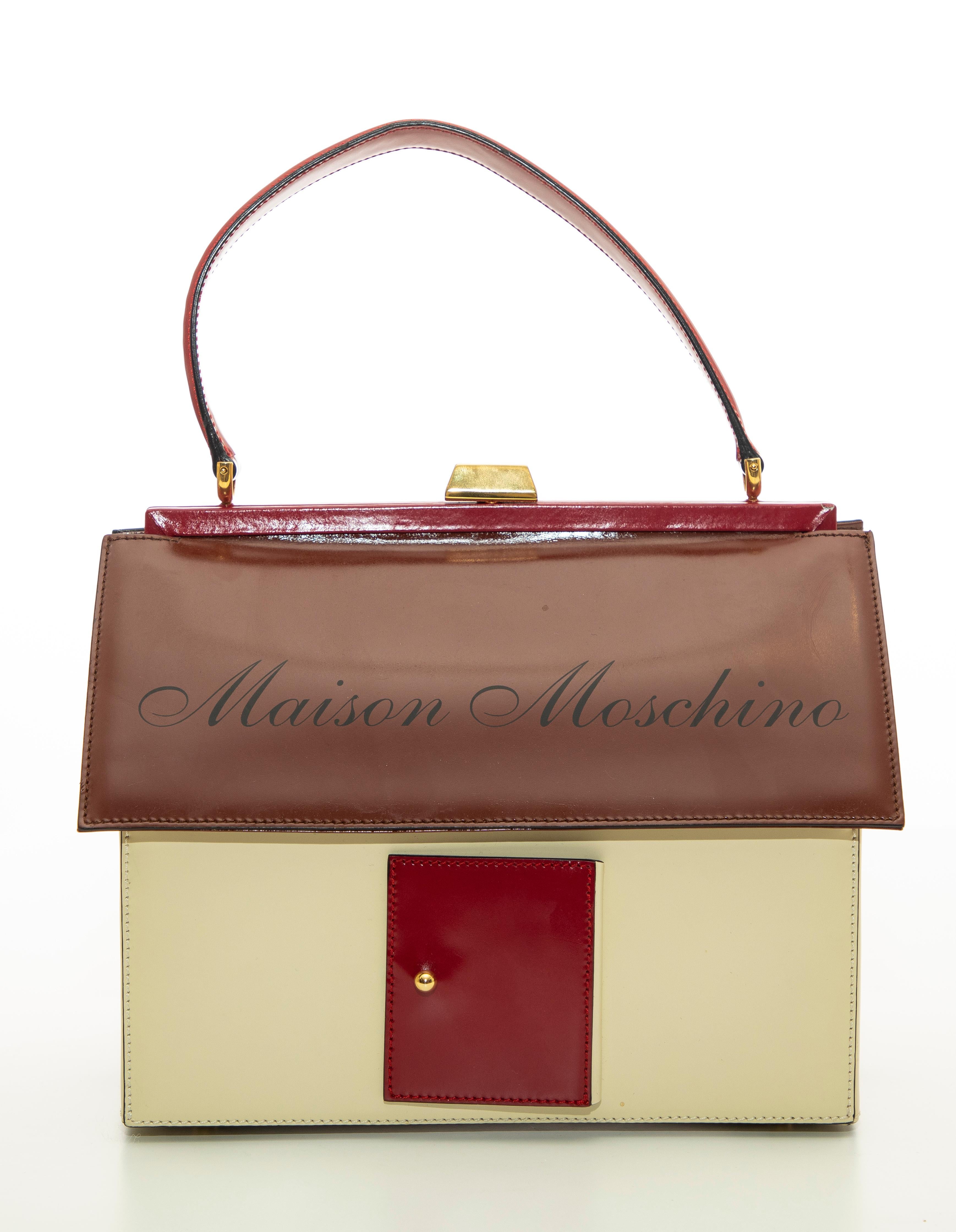   Moschino, Circa: 1991 house shaped top handle leather handbag with front door that opens to conceal a mirror, gilt metal push-lock clasp, protective feet at base and jacquard woven lining.


Handle Drop: 5, Height: 8, Width: 8.5, Depth: 5.25
