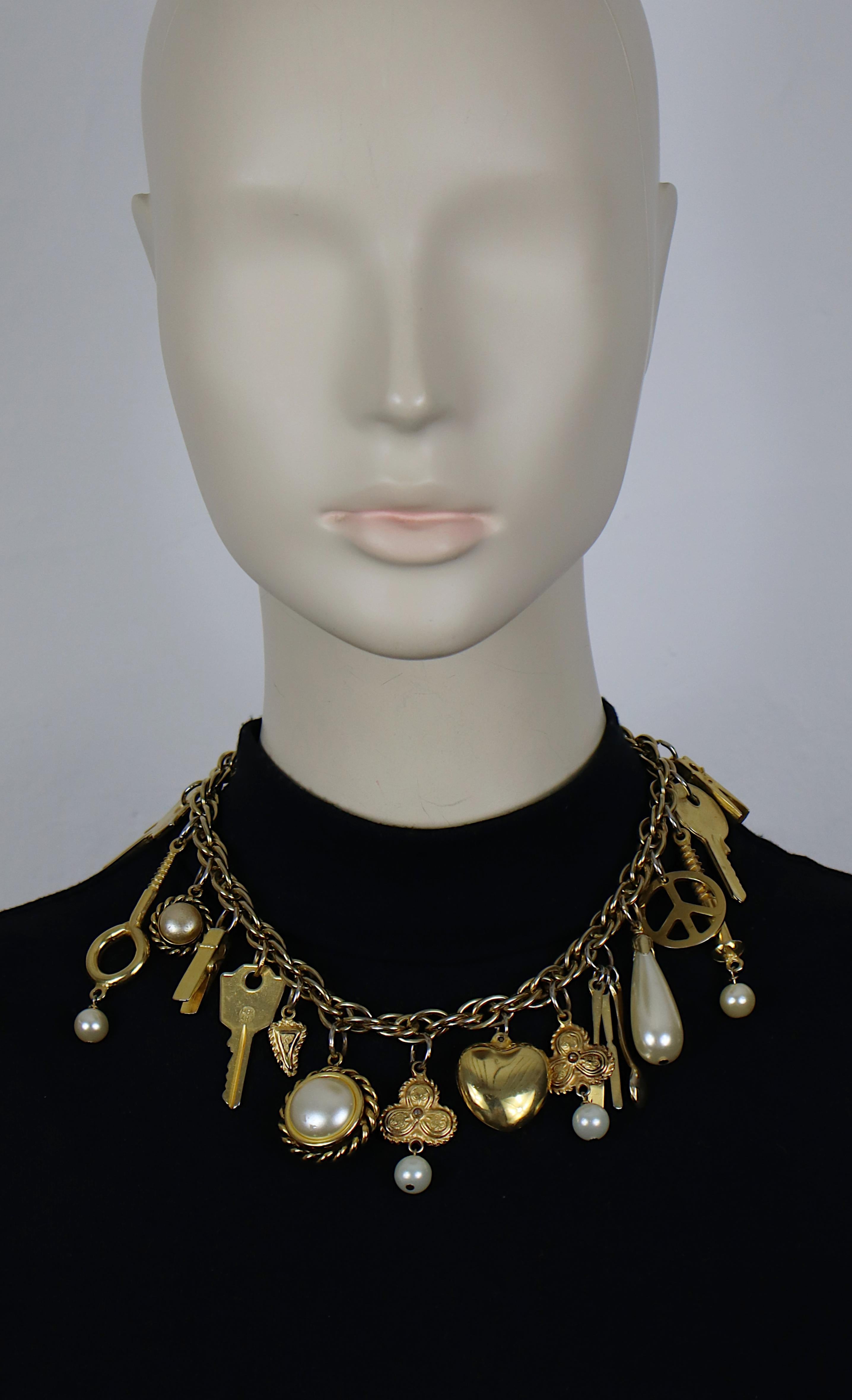 Collana a catena vintage in tonalità oro di Moschino con vari charme: chiavi, mollette, set di posate, viti, cuore, segno di pace, perle finte...

Chiusura a levetta.

MOSCHINO in rilievo.

Misura indicativa: lunghezza circa 42 cm (16,54