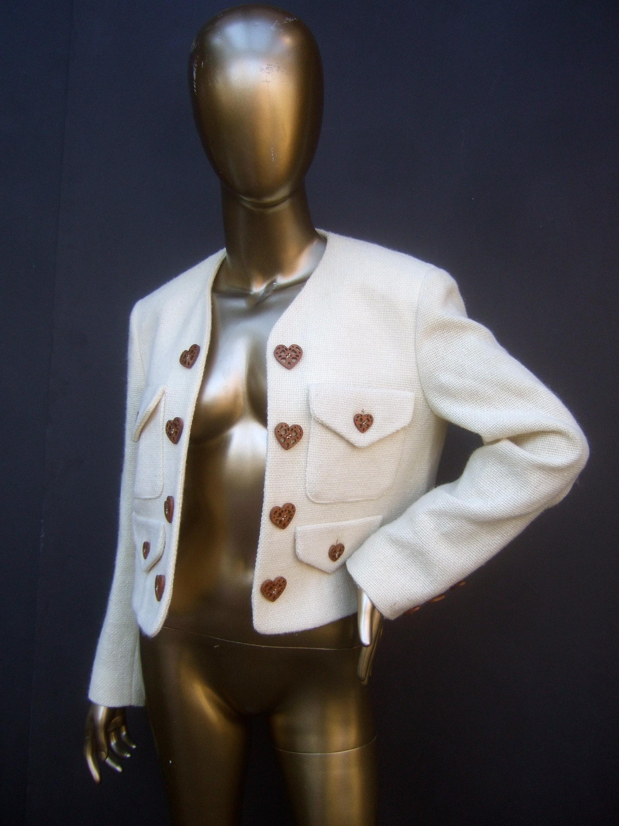 Moschino Italy Cream laine wool wood heart button jacket US Size 8 

The stylish Italian jacket is constructed with textured coarse laine wool. Adorned with a collection of carved wood heart shaped buttons. The pair of upper chest pockets have