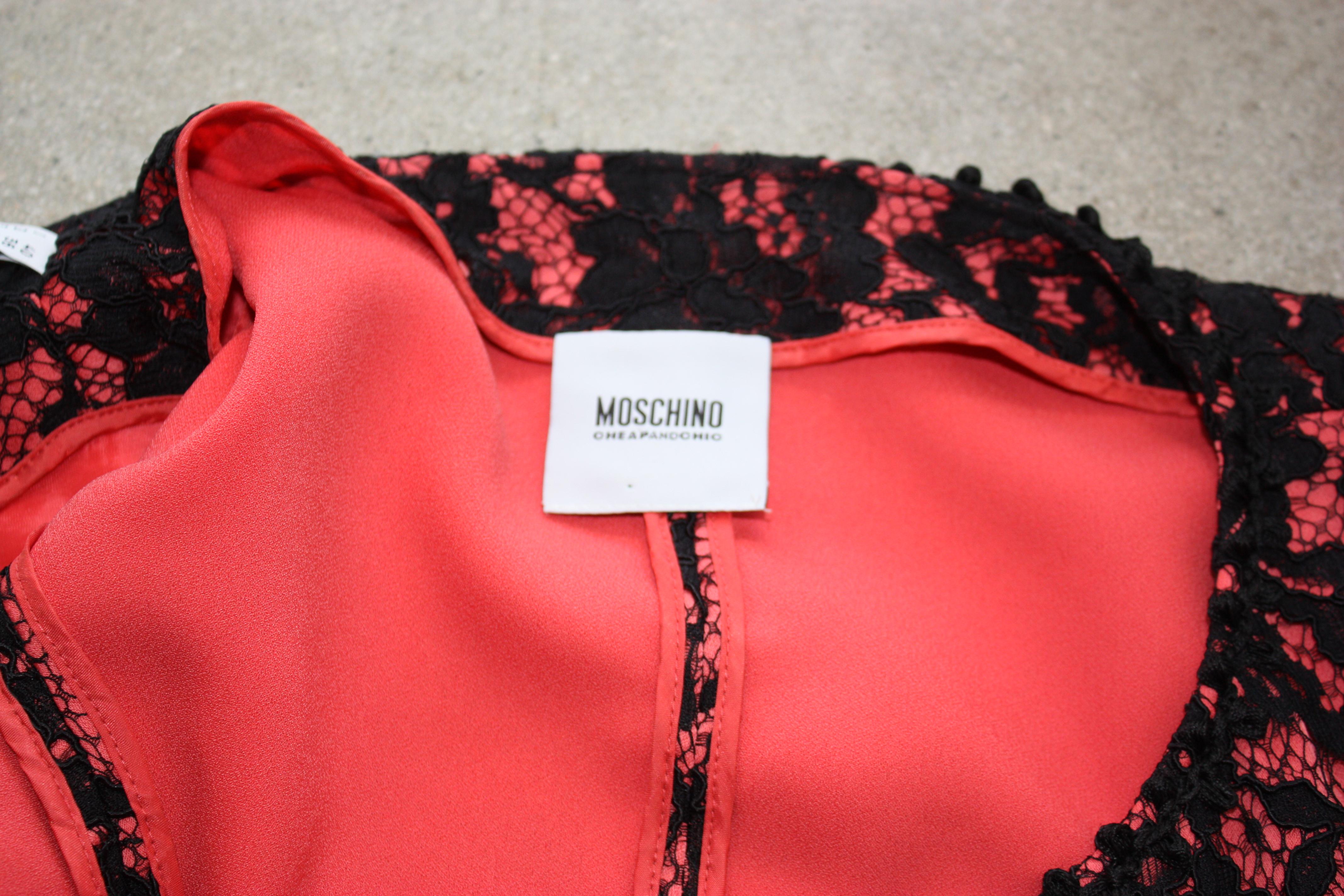 Moschino Cheap and Chic black and pink lace dress with bow waist detail. 
The coat dress has snap closures down the front, and could be worn as an overcoat or dress.

60% rayon, 40% polyamide. Lining 100% polyester.

Size 6.