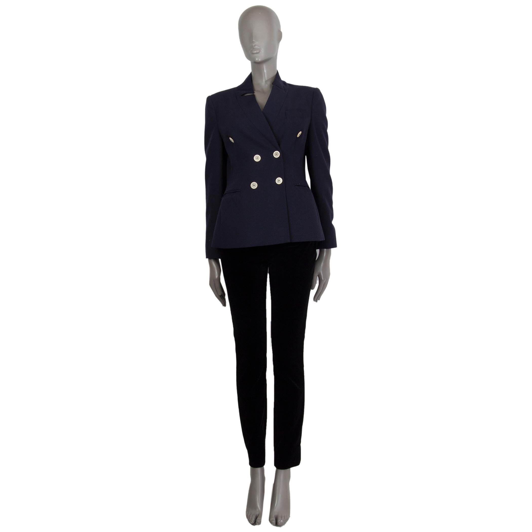 100% authentic Moschino double-breasted blazer in navy wool (100%). With notch collar, two gathered welt pockets on the front, and buttoned sleeves. Closes with ivory horn buttons on the front. Lined in black and red acetate (60%) and rayon (40%).