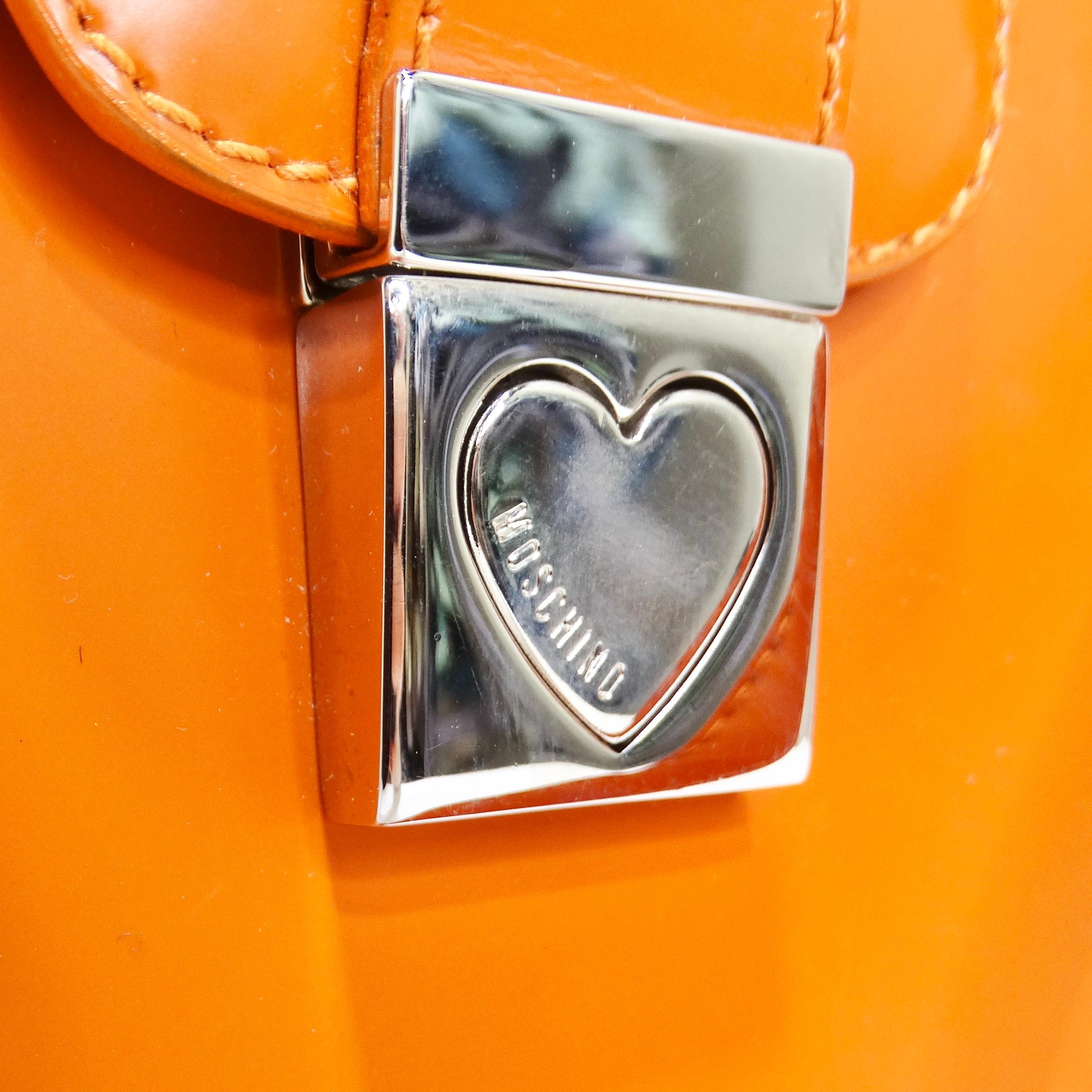 Voici le sac à main en cuir Moschino Orange Top Handle - une déclaration de mode qui allie style audacieux et praticité. Libérez la fashionista qui sommeille en vous avec ce sac à main en forme de croissant dans une teinte orange vibrante. Fabriqué