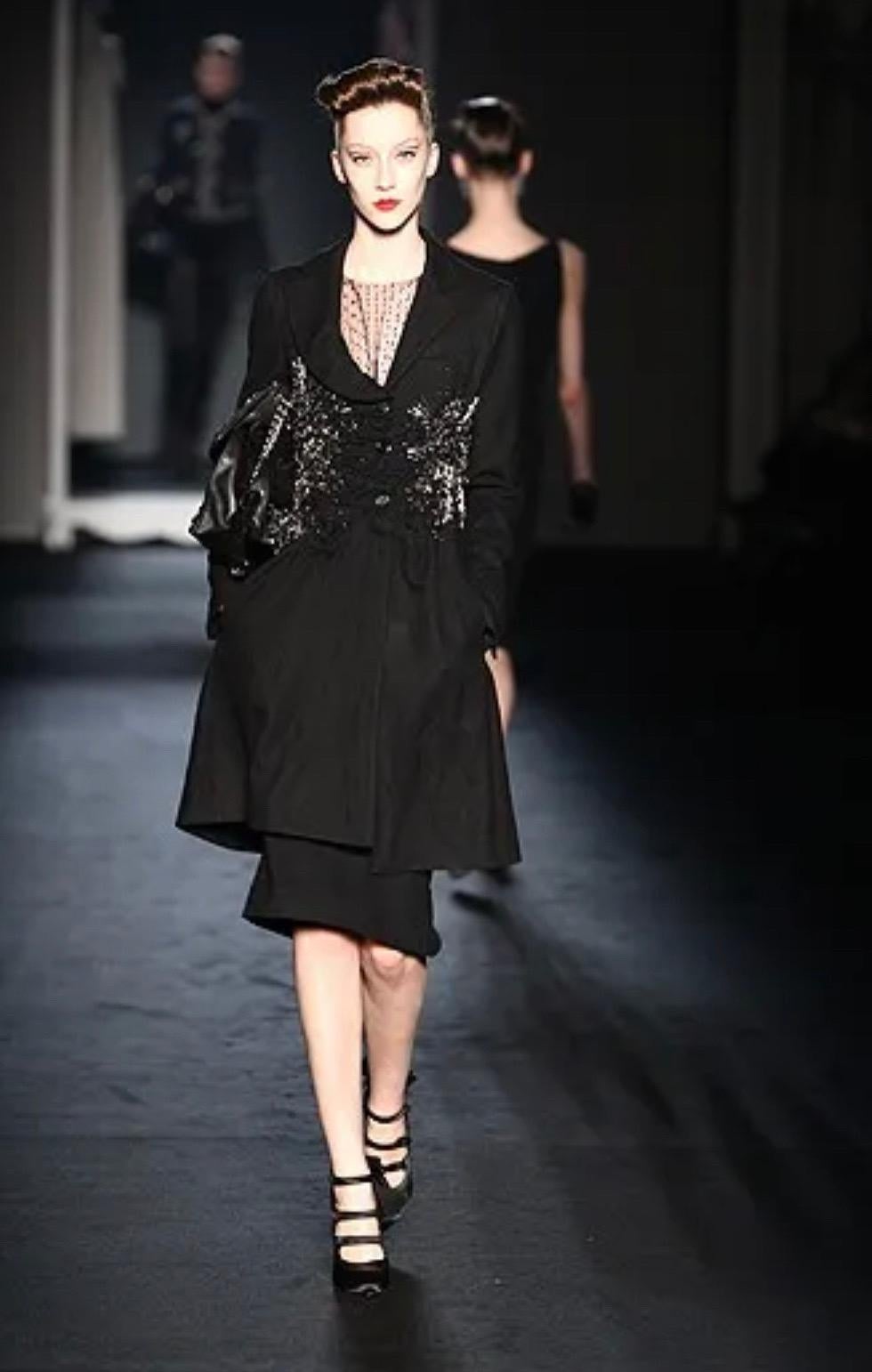This striking Moschino coat evokes rebellious elegance with a punk edge. From the Fall Winter 2009 collection and as seen on the runway. Crafted from structured black wool, the tailored silhouette features dramatic ruching down the front.  Intricate