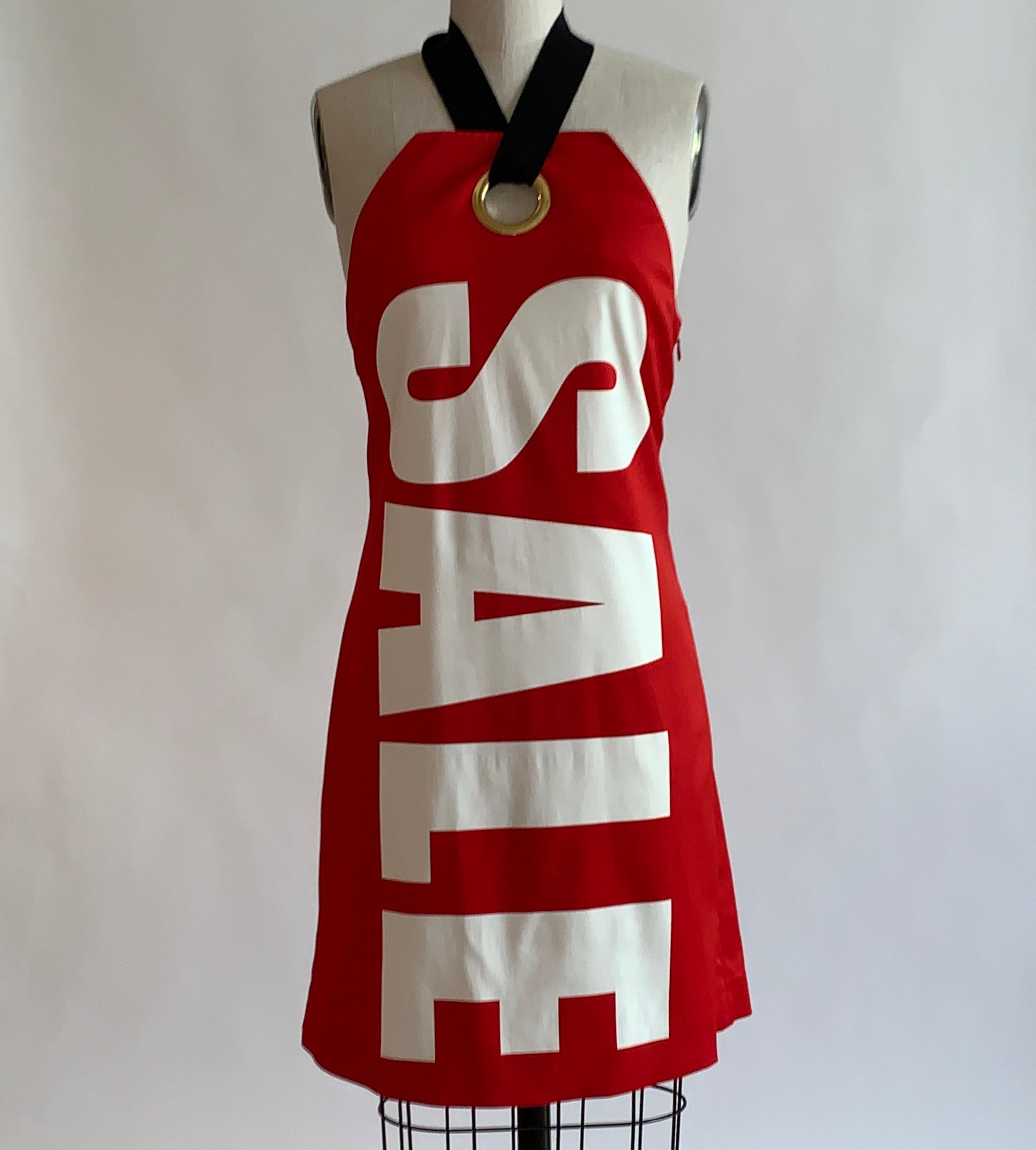 Moschino red and white halter dress designed to look like a retail hang tag with block print reading SALE at front from Jeremy Scott's Resort 2016 collection. Big gold grommet at center chest where black grosgrain strap loops through to tie around