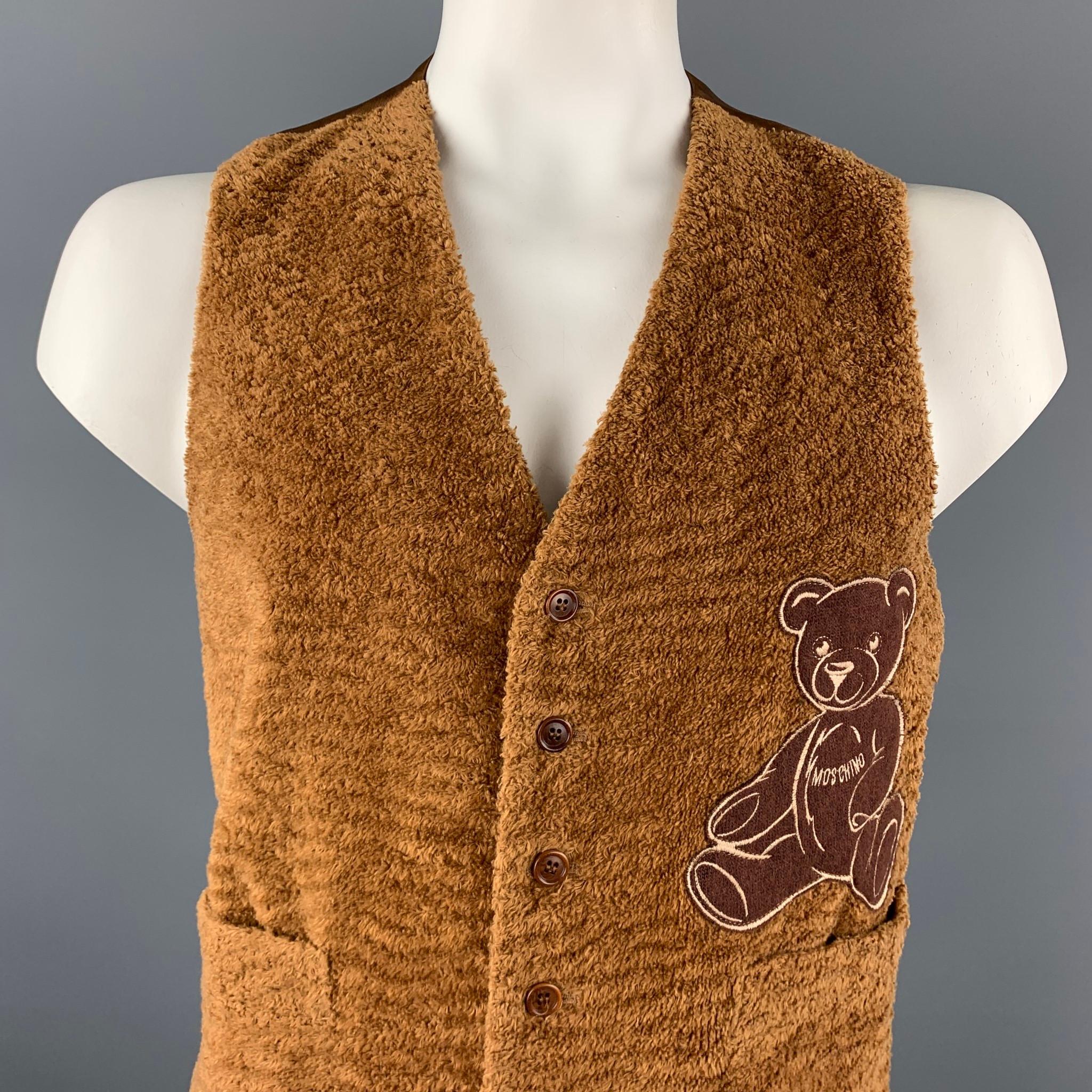MOSCHINO vest comes in a brown textured cotton with a bear embroidered design featuring slit pockets, back belt, and a buttoned closure. Made in Italy.

Very Good Pre-Owned Condition.
Marked: 44

Measurements:

Shoulder: 14 in. 
Chest: 42 in.