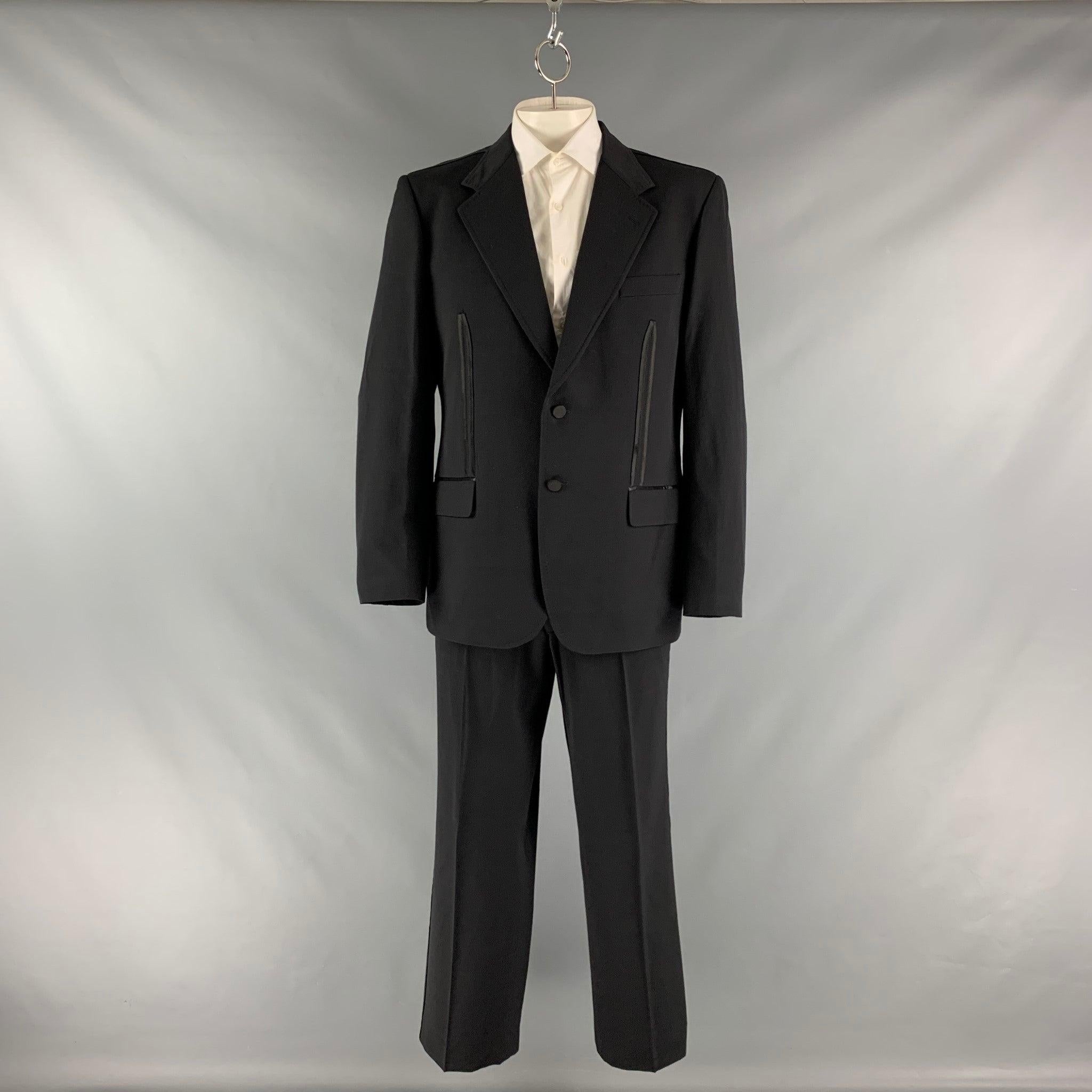 MOSCHINO tuxedo suit comes in a black polyamide blend material with a full liner and includes a single breasted, double button sport coat with a notch lapel and matching flat front trousers. Made in Italy.Very Good Pre-Owned Condition. Moderate