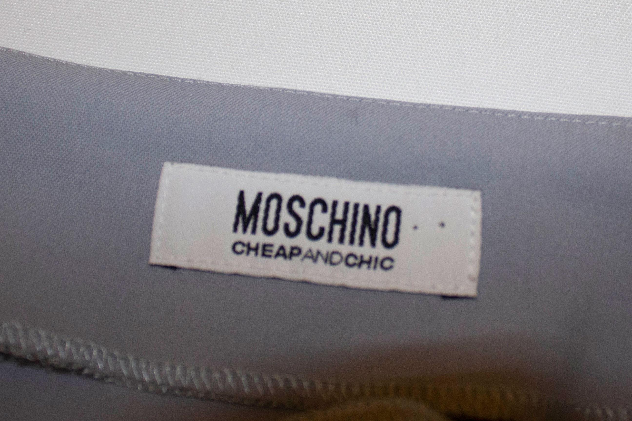 A pretty skirt suit by Moschino . In a  pretty powder blue wool with silver trim , the jacket has a three button fastening and button cuffs. The short skirt is unlined. Size UK 8
Meaurements: Jacket bust 34'', length 23 Skirt waist 26'', length 17''