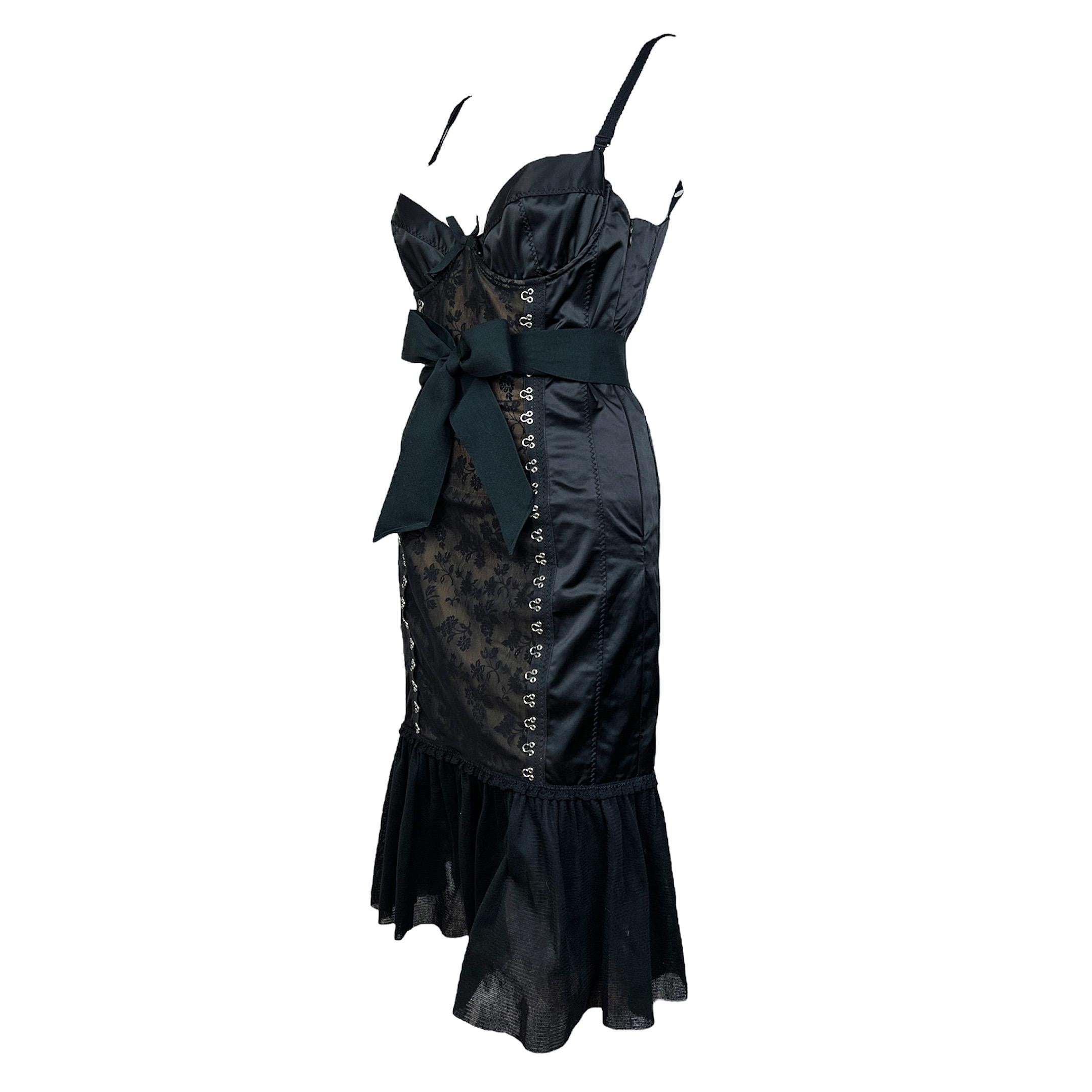 Superbe robe de lingerie noire Moschino Printemps 2004 avec dentelle et crochets sur le corsage, et volants au bas comme vu sur le défilé dans une version rose. La robe est ornée d'un nœud en ruban gros grain à la taille et comporte une fermeture