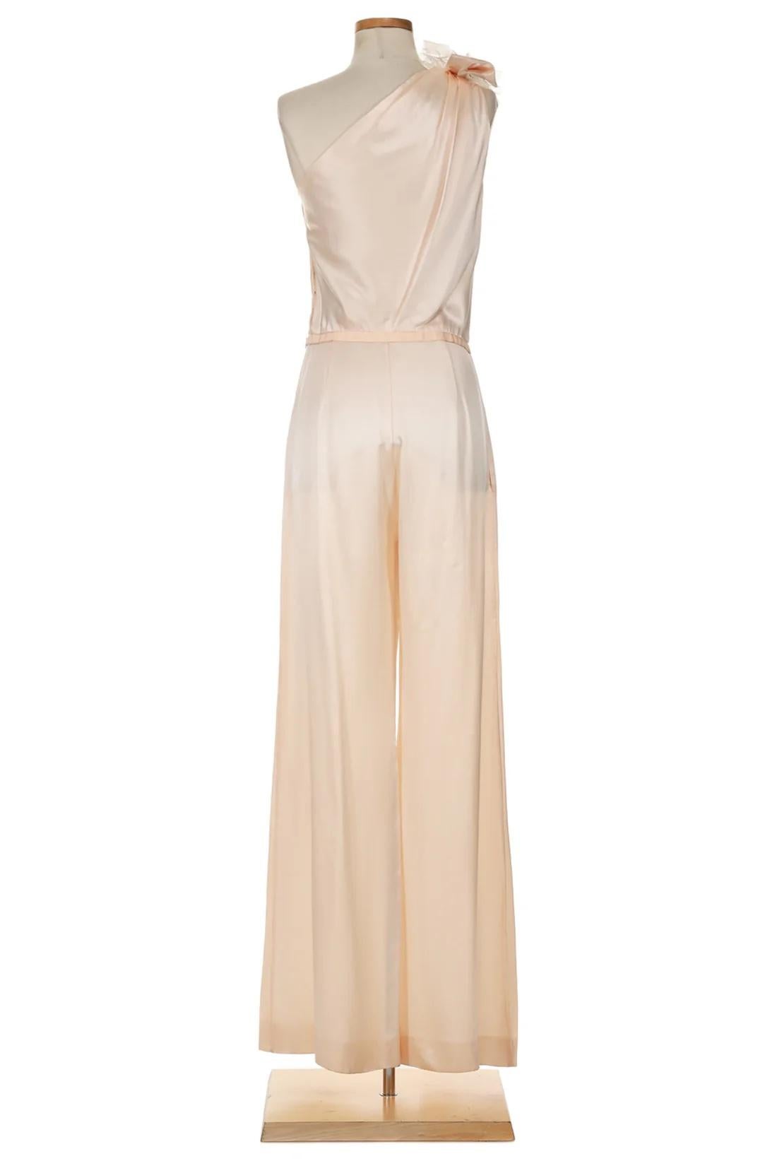 VINTAGE GRACE NY

This Moschino Spring 2014 jumpsuit exudes a soft, feminine elegance with a luxurious touch. Crafted from smooth, pale peach silk, the one-shoulder design drapes gracefully across the body, showcasing refined tailoring and a