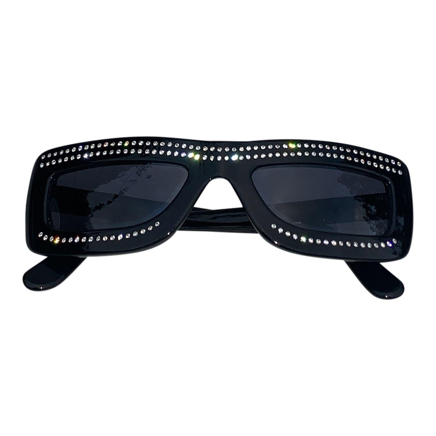 These Moschino sunglasses are a true fashion statement.
The black frames are made of high-quality acetate and feature a classic rectangular shape. The arms are adorned with a cut-out design that adds a touch of edginess to the overall look. The