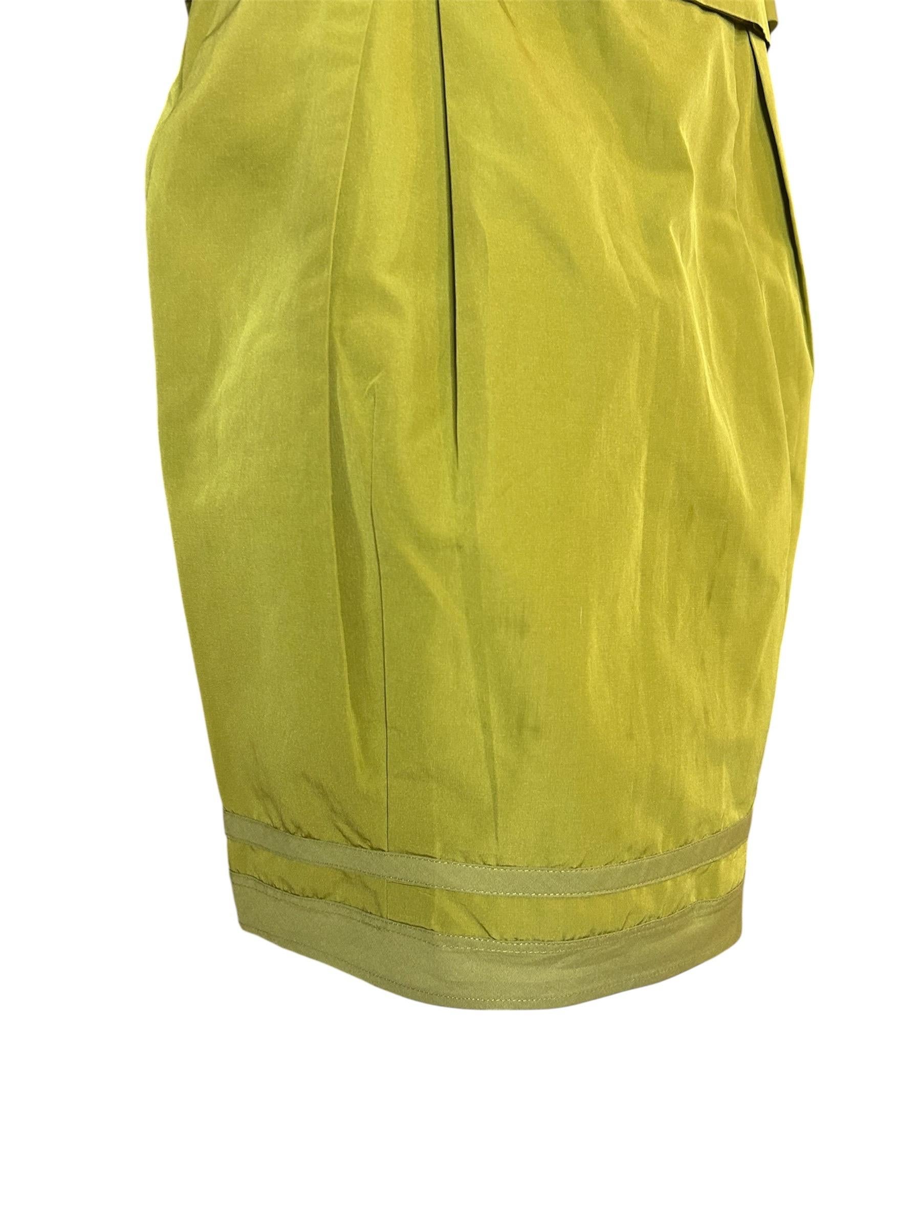 Questo completo vintage con gonna di Moschino degli anni '90 esemplifica l'approccio giocoso ma raffinato del marchio alla sartoria. Realizzato in un sorprendente misto seta verde chartreuse con una sottile lucentezza, l'ensemble di due pezzi
